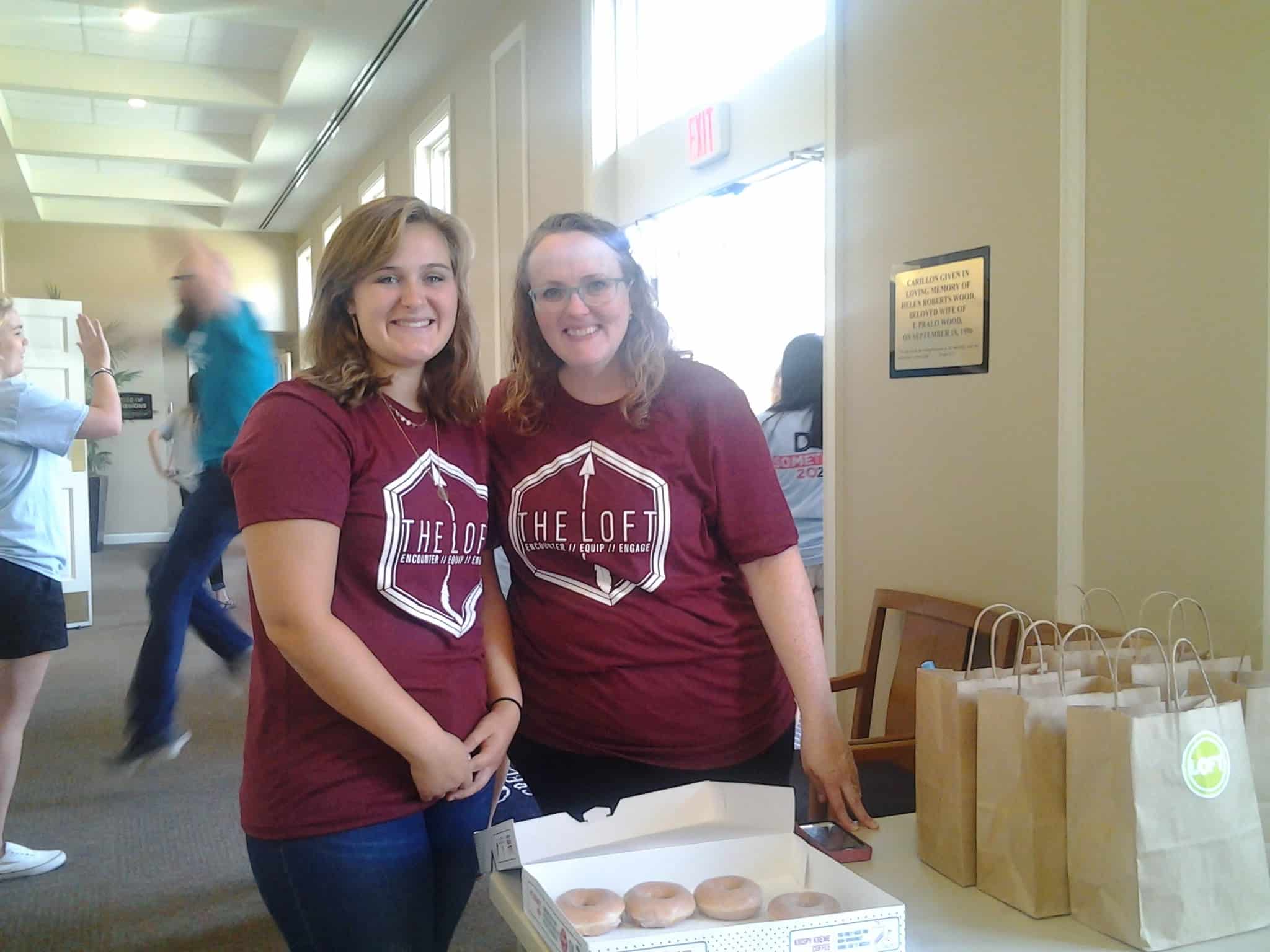 Two women from The Loft &nbsp;greeted students with doughnuts while Jody Jennings greeted the mentors with entusiastic high fives. Photo credit: Carrie Henderson