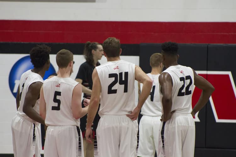 The Crusaders huddle up as Daniel Burchette lines up at the free throw line. Photo credit: Triston Evans
