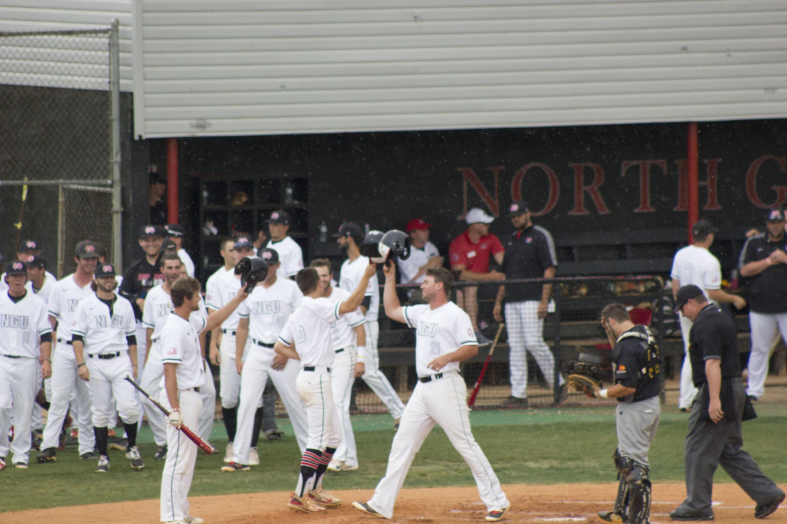 Connor Grant (center) and teammates congratulate Nathaniel Maggio (right) when he approaches home plate following his two-run home run.