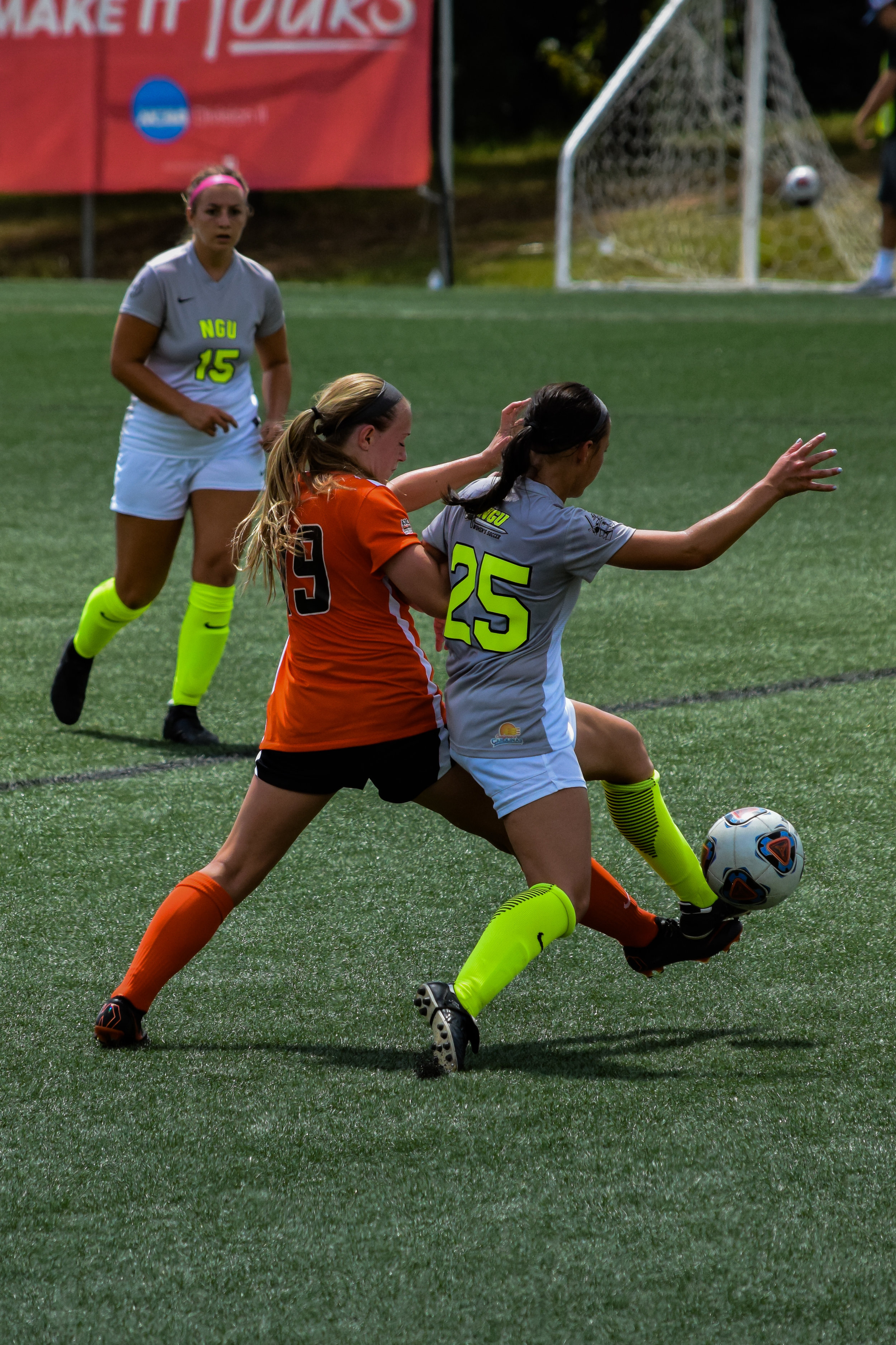 #25 Natalie Johnson risks falling as she goes to pass the ball to her teammate as #15 Karly Denaburg runs to help.