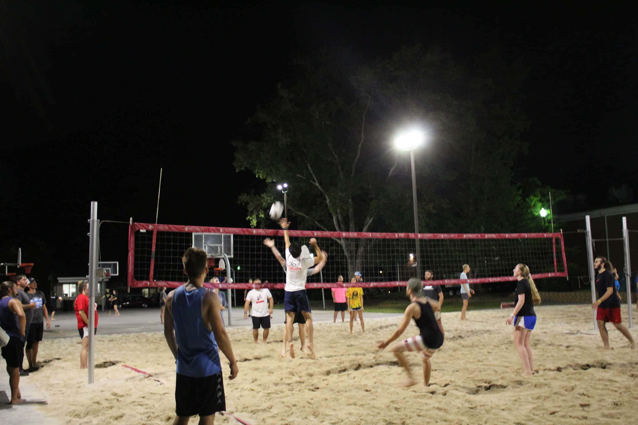 As a player from one team begins to spike the ball over the net, a player from the other team jumps in an attempt to block the spike.
