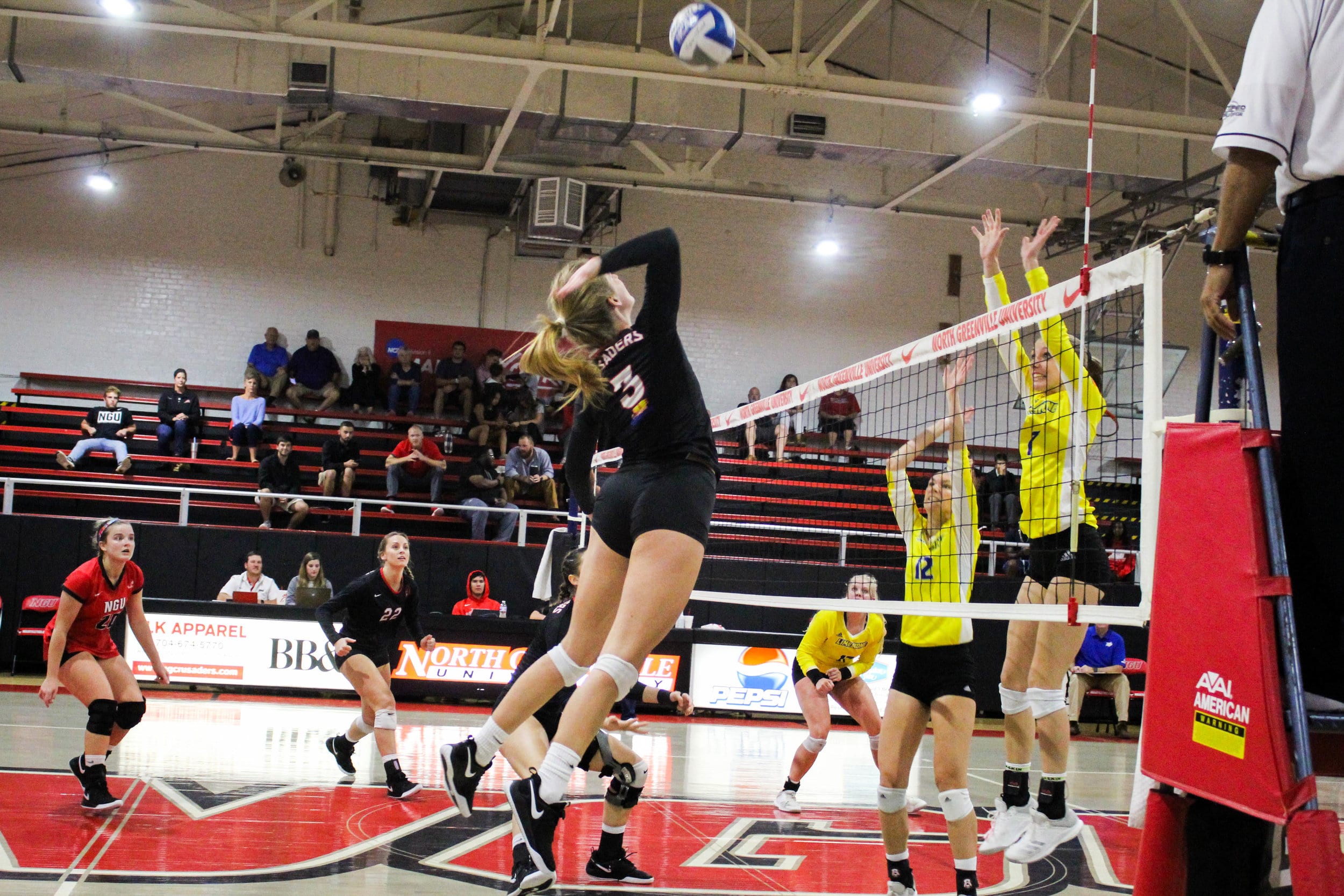 Junior Emma Pepper (3) jumps to spike the ball past two of Limestones players jumping on the other side of the net.