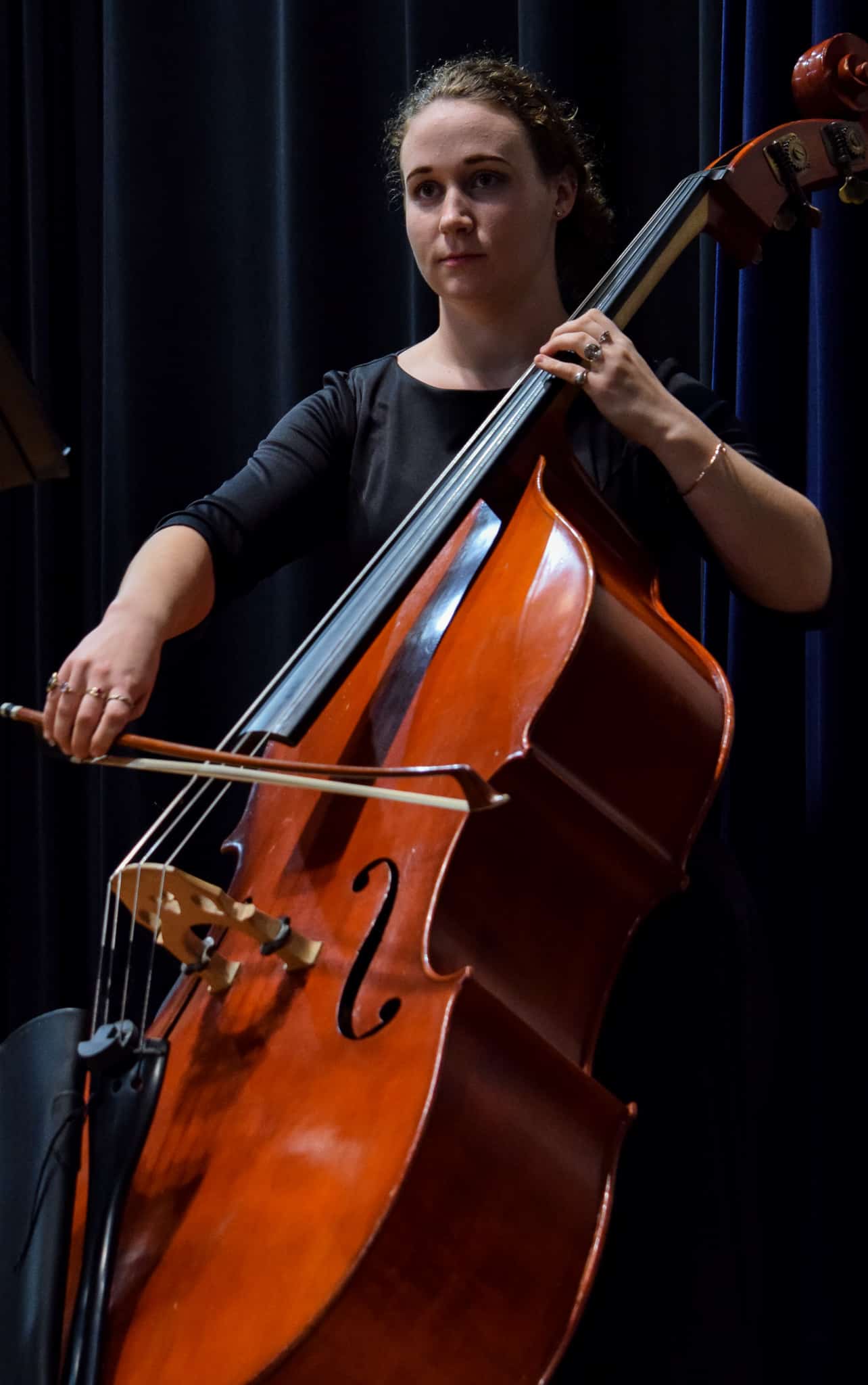 Senior, Francesca Scott looks off to the distance as she practices her double bass before the concert.