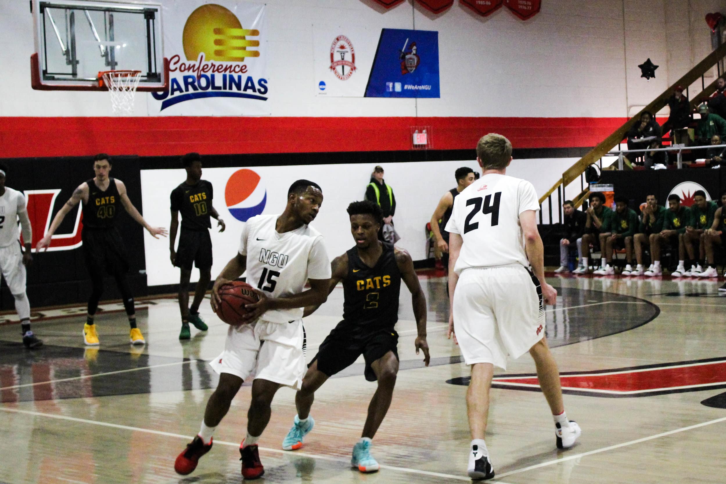 While a player from the opposing team defends both freshman Joe Conley (24) and sophomore Ryan Mobley (15), Conley passes the ball to Mobley.