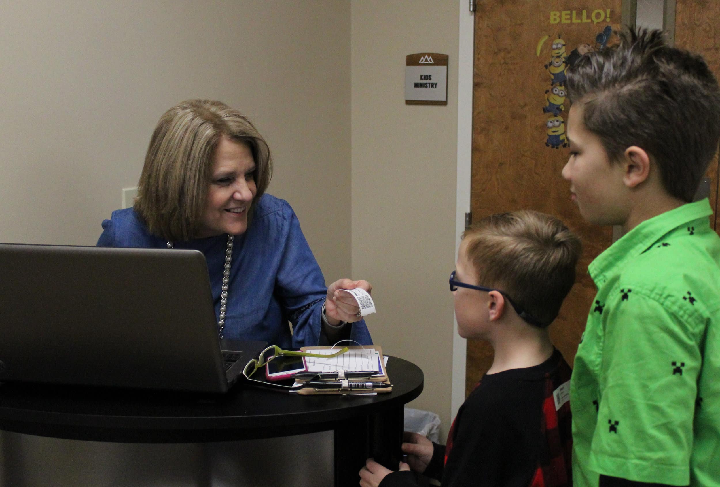 On Sunday mornings, children from ages one to 12 are electronically checked in specifically into their class according to age. Here, LeeAnn Streetman, the childrens pastors wife, welcomes our youth Jaxson McManus and Brian Fowler.