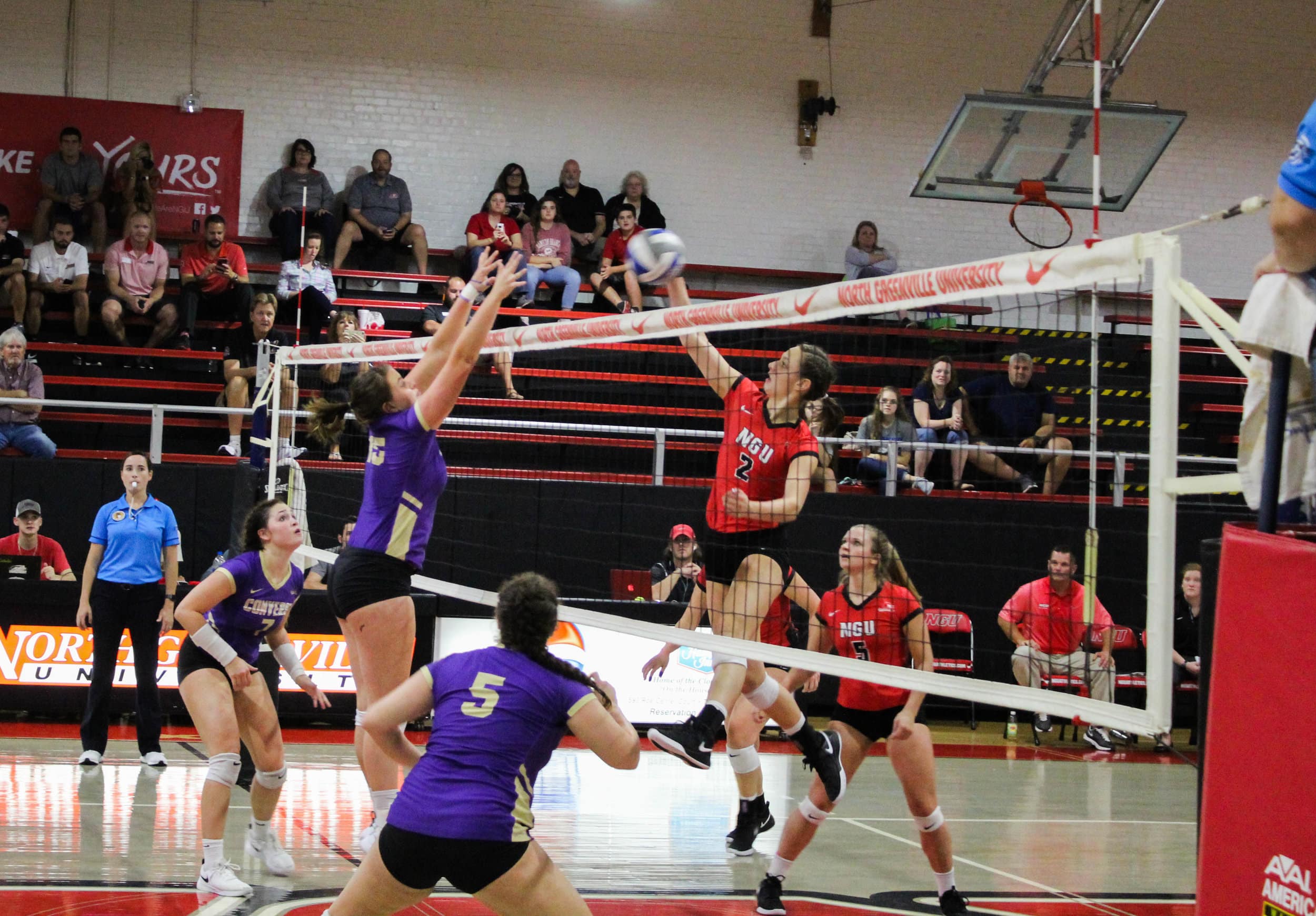 Freshman, Paige Beisecker (2) spikes the ball over the net as a player from Converse jumps in an attempt to block the ball.