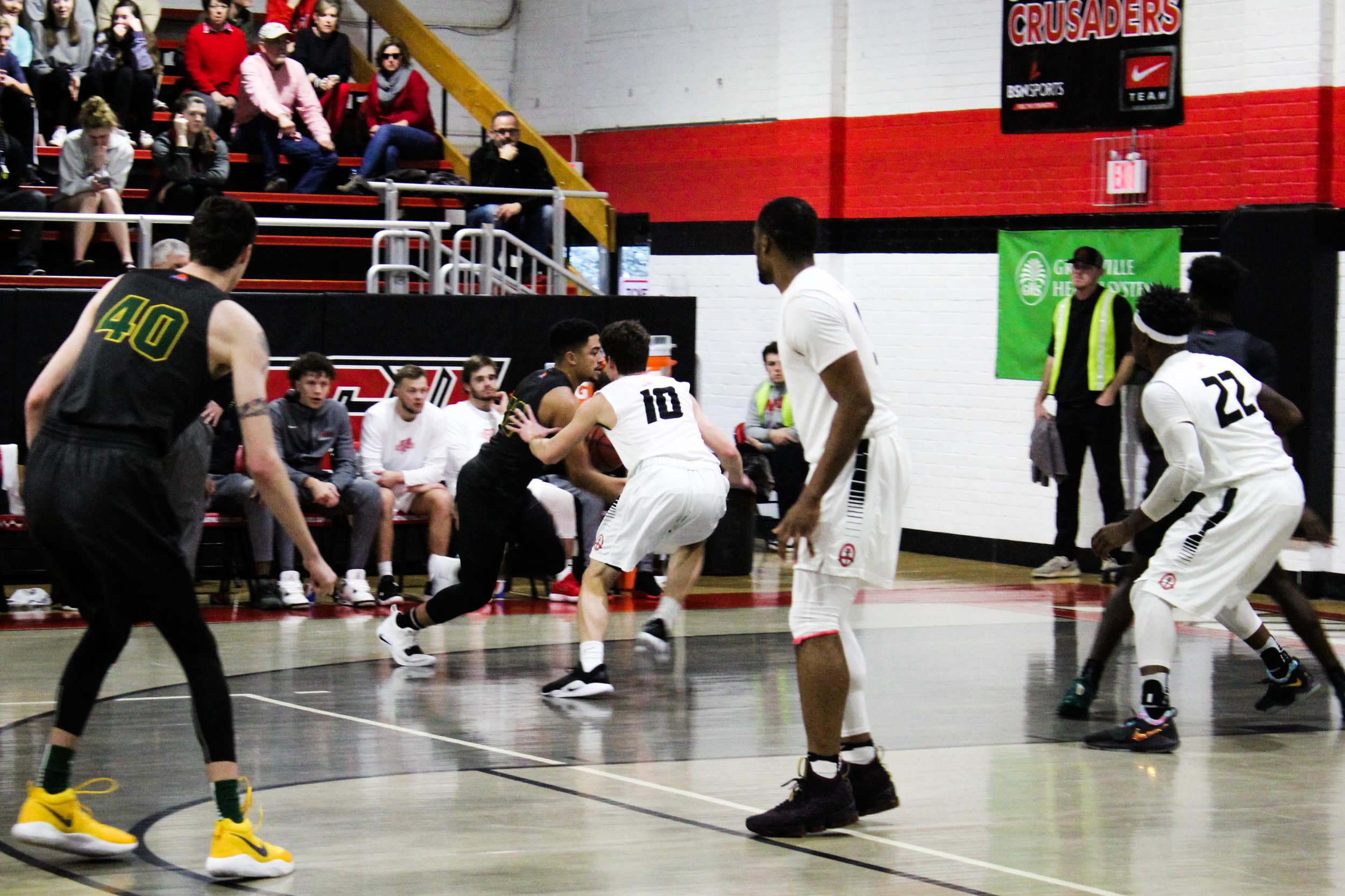 Freshman Caleb Arrington (10) guards the point guard from Lees-McRae College as he dribbles in for a layup.