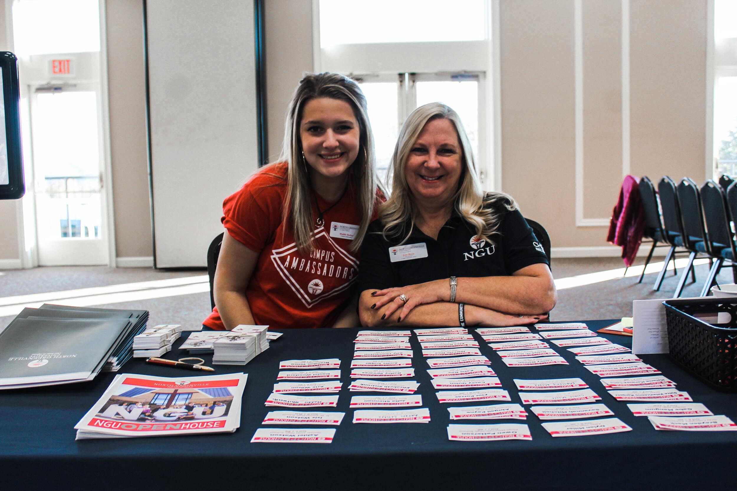 Maddie Barber (freshman) and Joan Moon (Campus Ambassador Advisor) handing out name tags to prospective students.