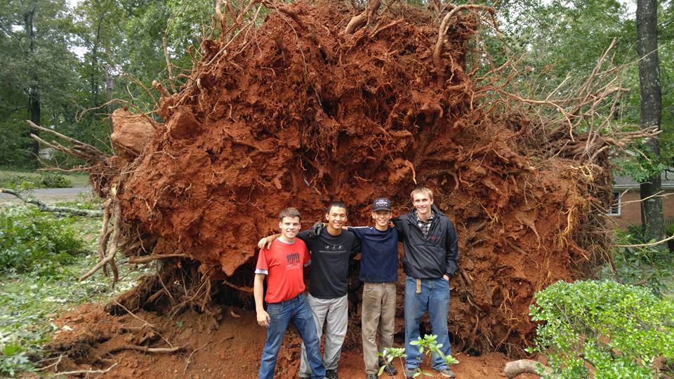 From left to right: NGU sophomore George Case, Josh Sundt, Caleb Sundt and sophomore Bradley Sundt in front of a tree root that fell near a house.