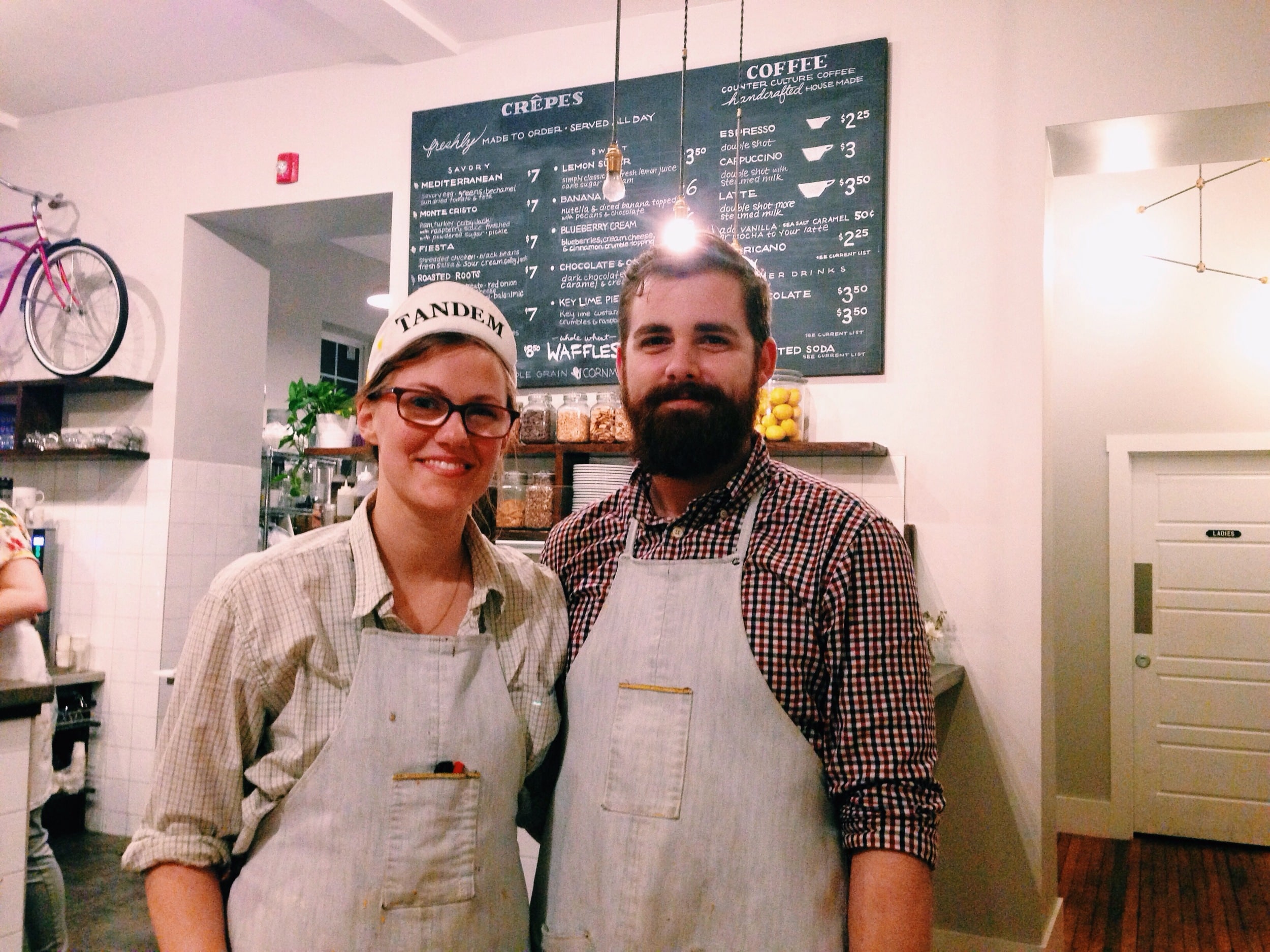 Brad and Kristen Hartman pose&nbsp;for a photo in front of Tandem's menu. See the light bulb above his head? His brilliant idea was Tandem.