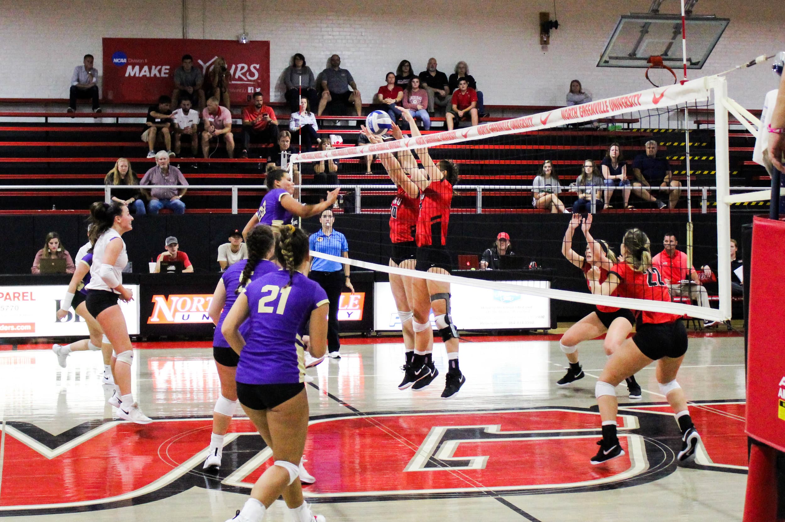 Catherine Lant (10) and senior, Annie Beisecker (17) both jump to block a spike from a Converse player.