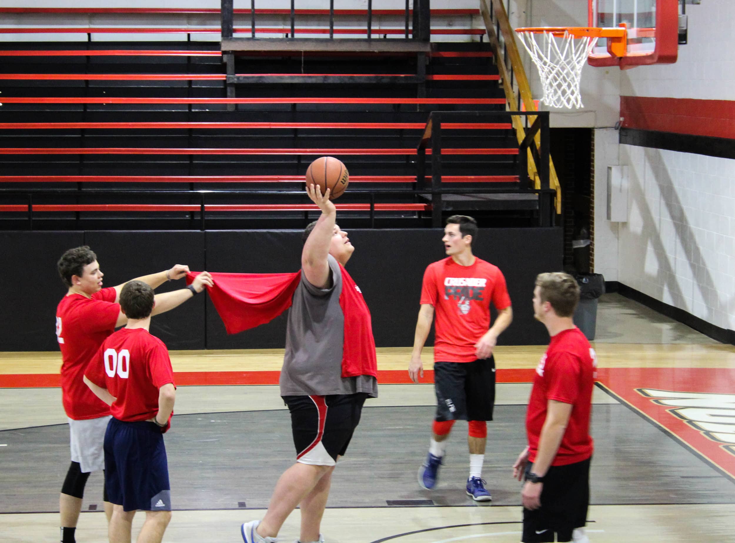 "The Walk-Ons take time to joke around while warming up for their game. Bo Felton prepares to shoot the ball while Jacob Herman makes his cape fly.