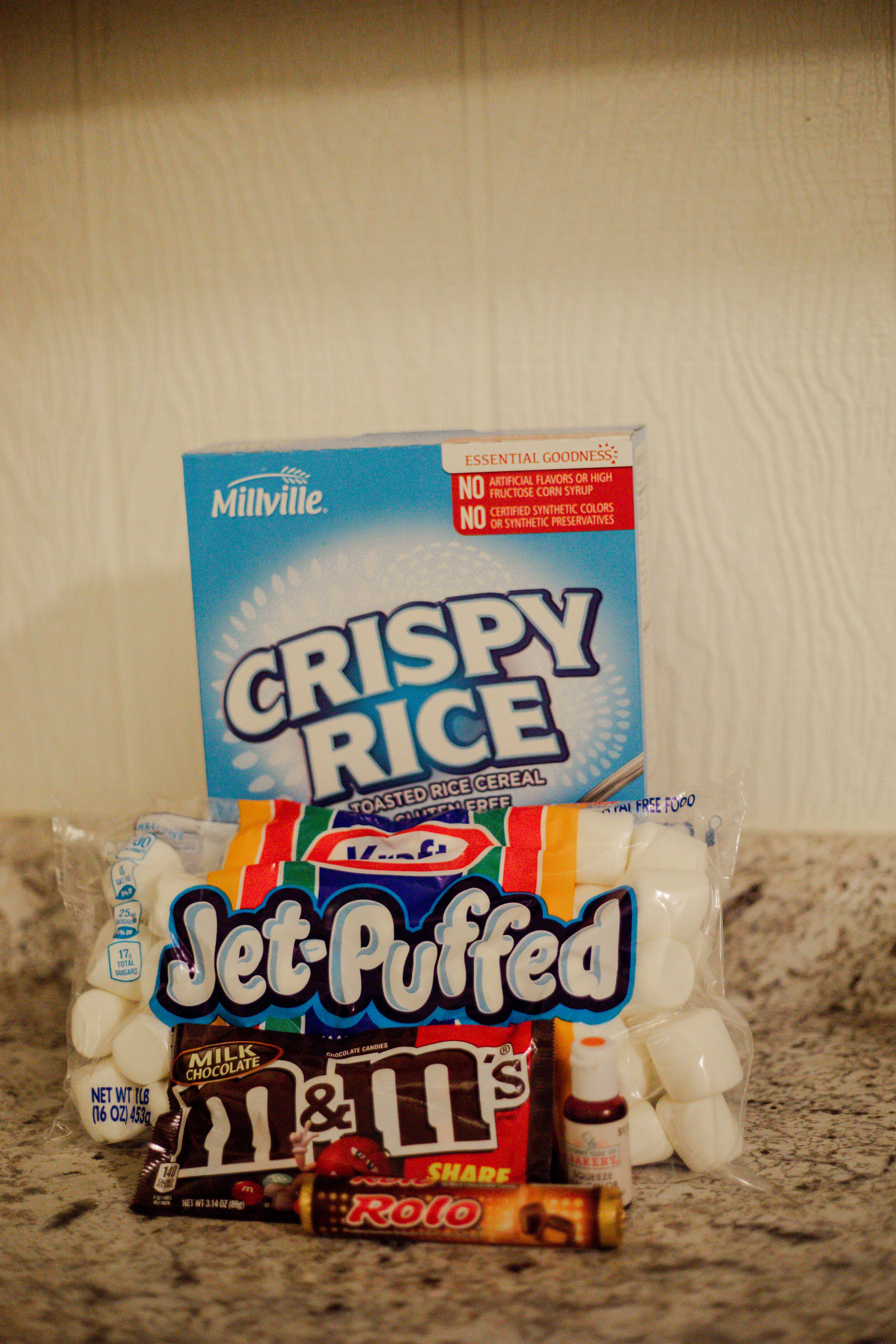 Here are all of the ingredients you will need to make this festive treat. Rice crispy cereal, marshmallows, m&amp;ms, Rolo candy and orange food coloring.