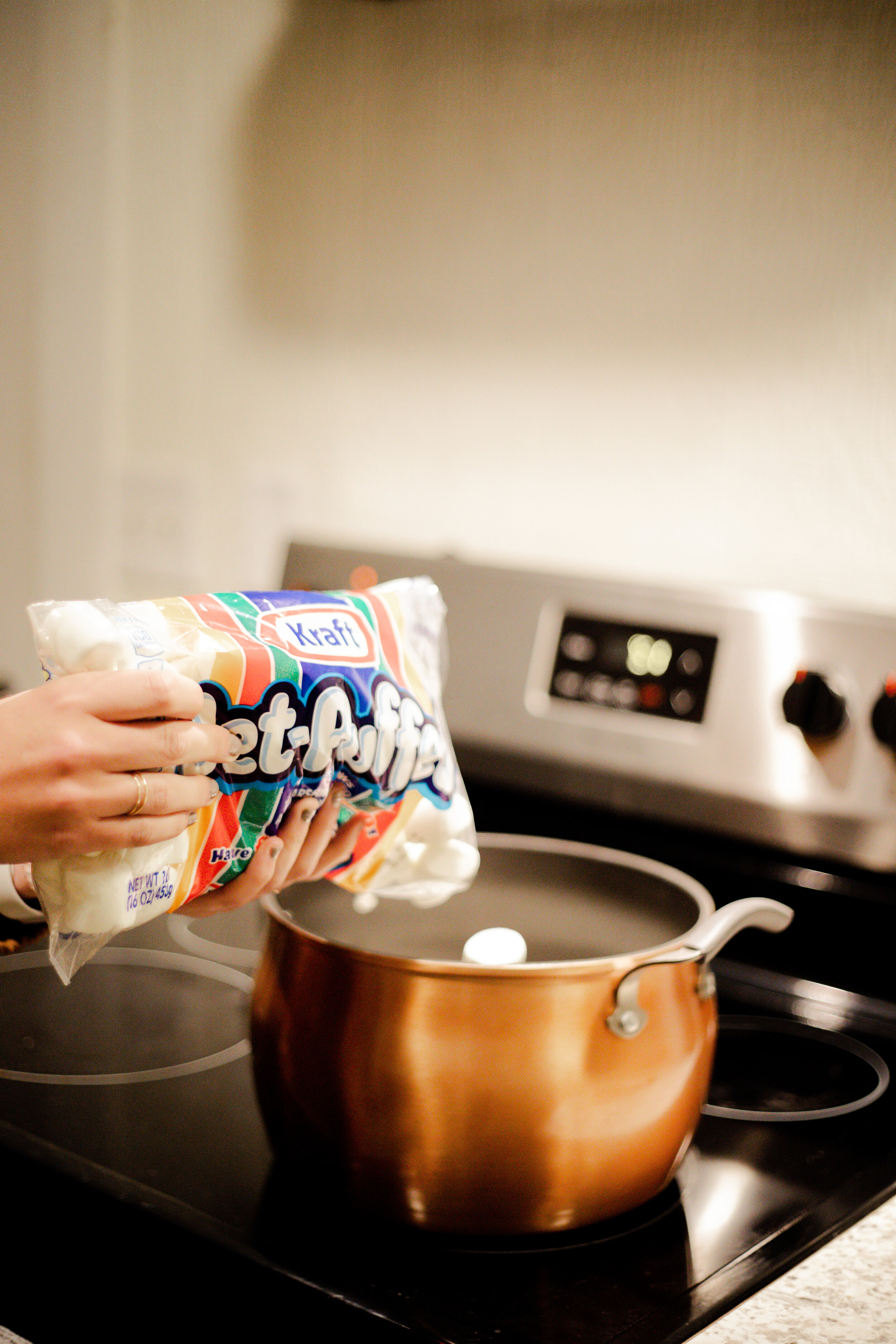 First, pour the whole bag of marshmallows into a large pot on the stove. Turn the stove to medium heat so that the marshmallows begin to melt.