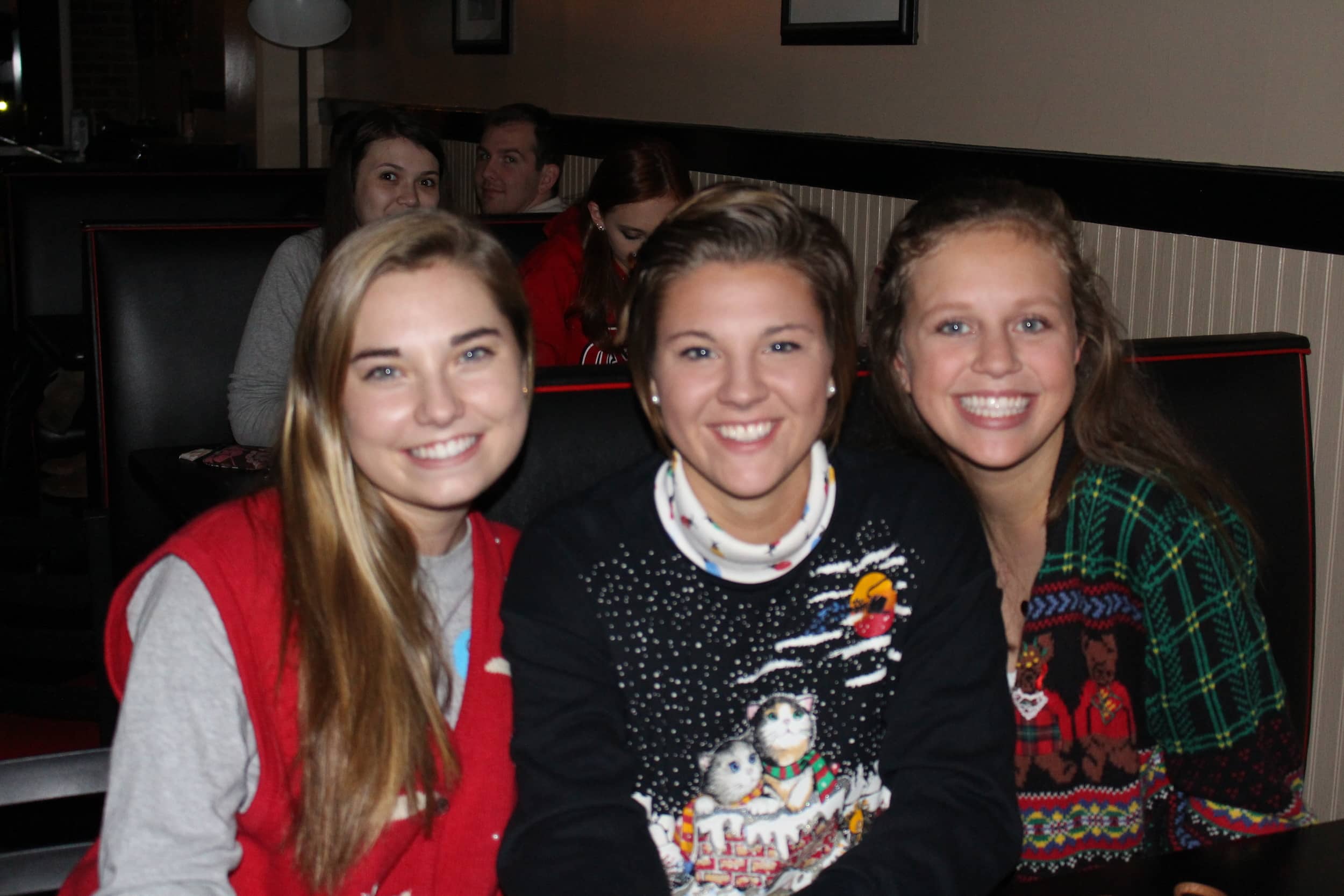 Olivia Hayes, Rebecca Watson and Siera Blackbird showing off their "Ugly Christmas sweaters" during the coffeehouse.