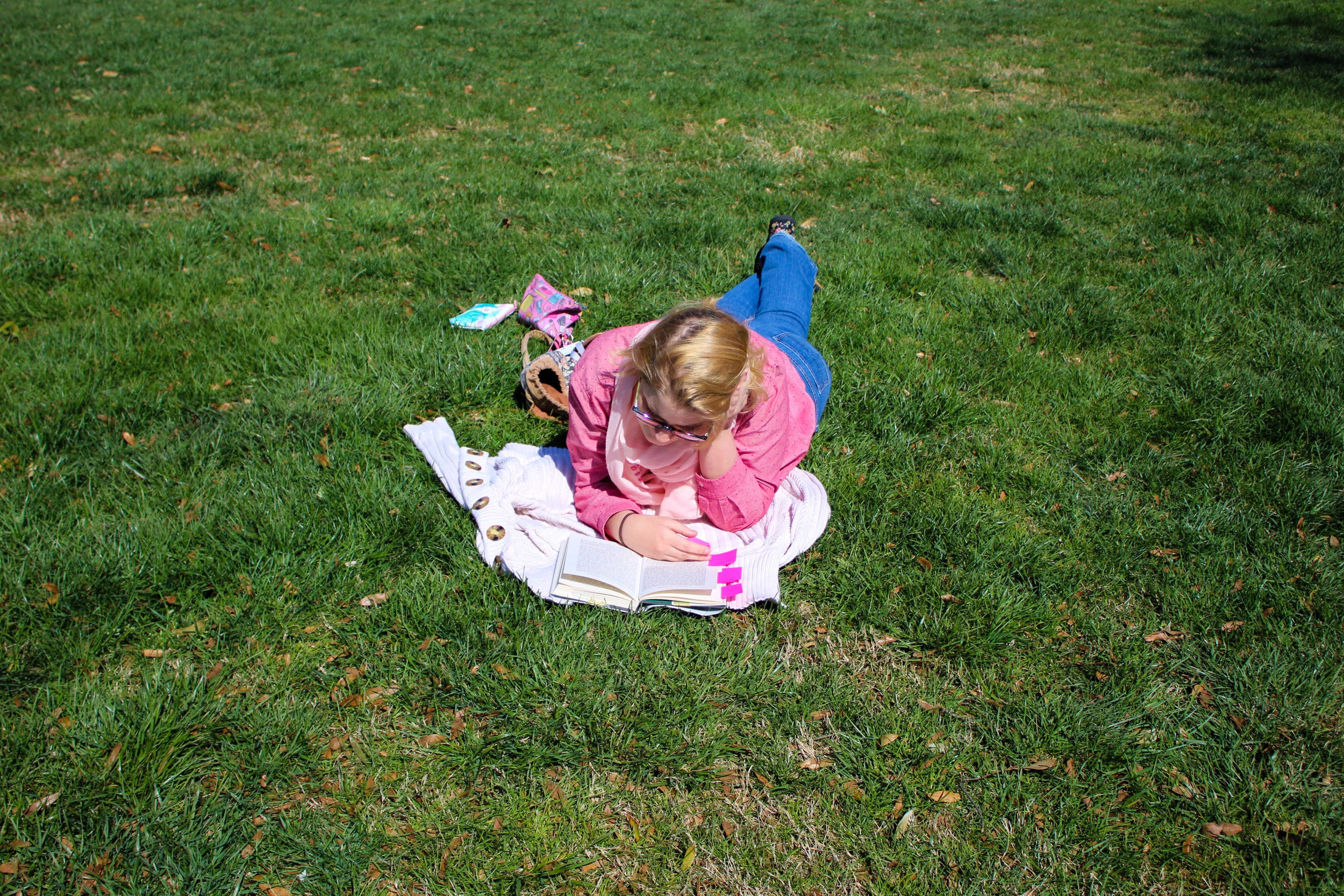 Linnea Stevens,&nbsp;a studio art major, enjoys the pleasant weather as she lays on the grass while reading.