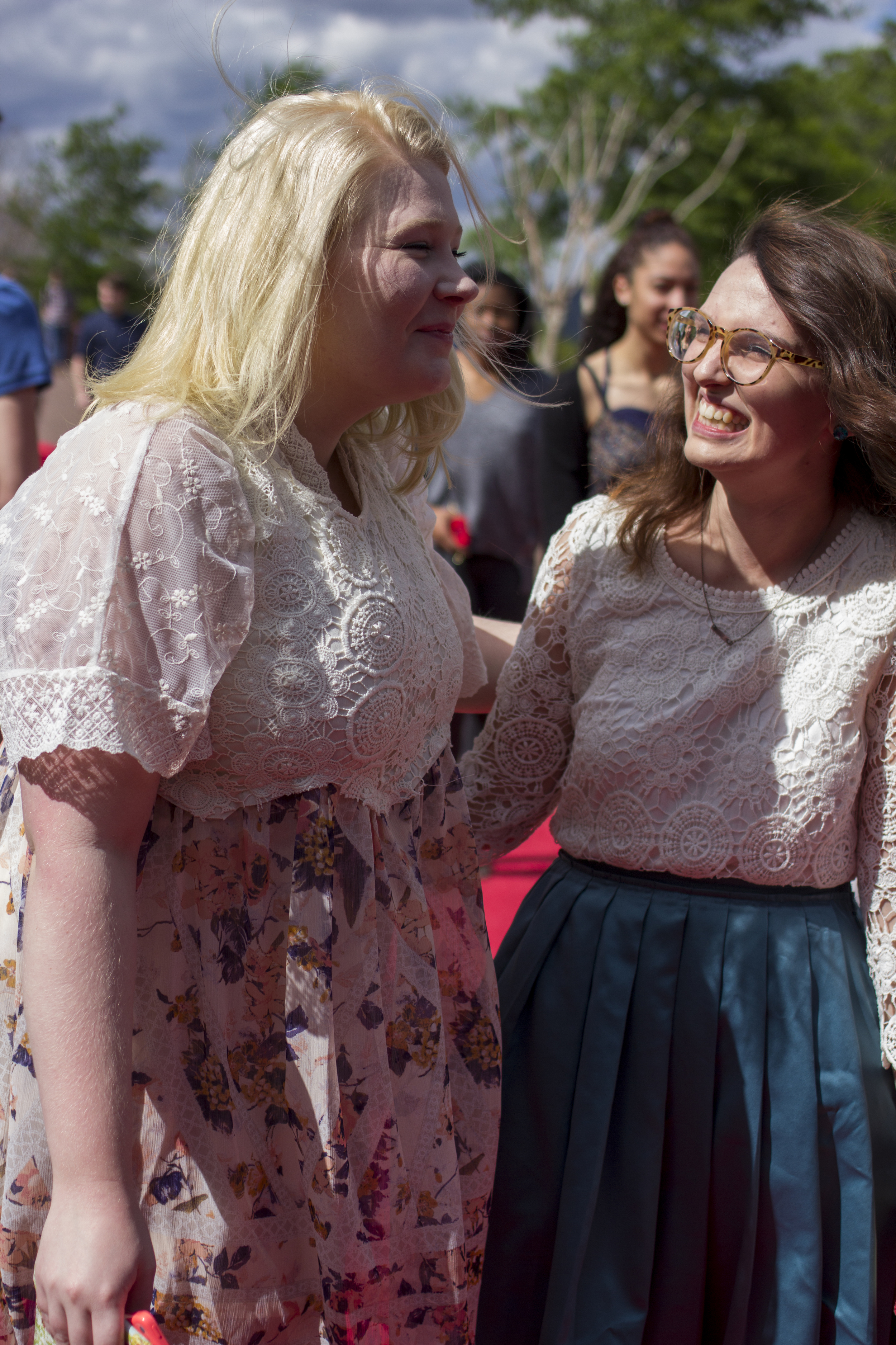 Rather than getting flustered,&nbsp;Victoria Pujdak and Emily Artus laugh at the high gusts of wind getting in the way of them getting a picture together wearing their matching styled dresses.