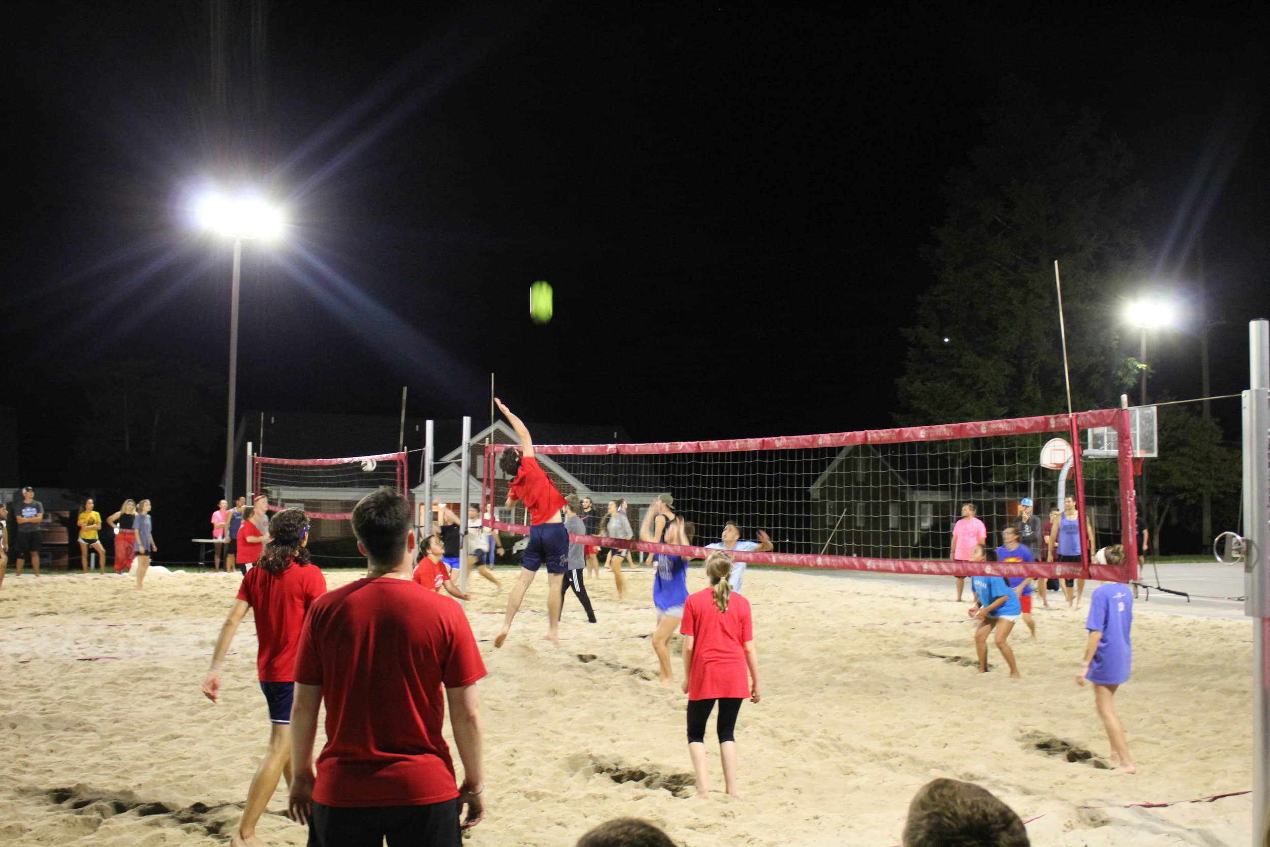 A player on the red team jumps to spike the ball over the net towards the blue team.