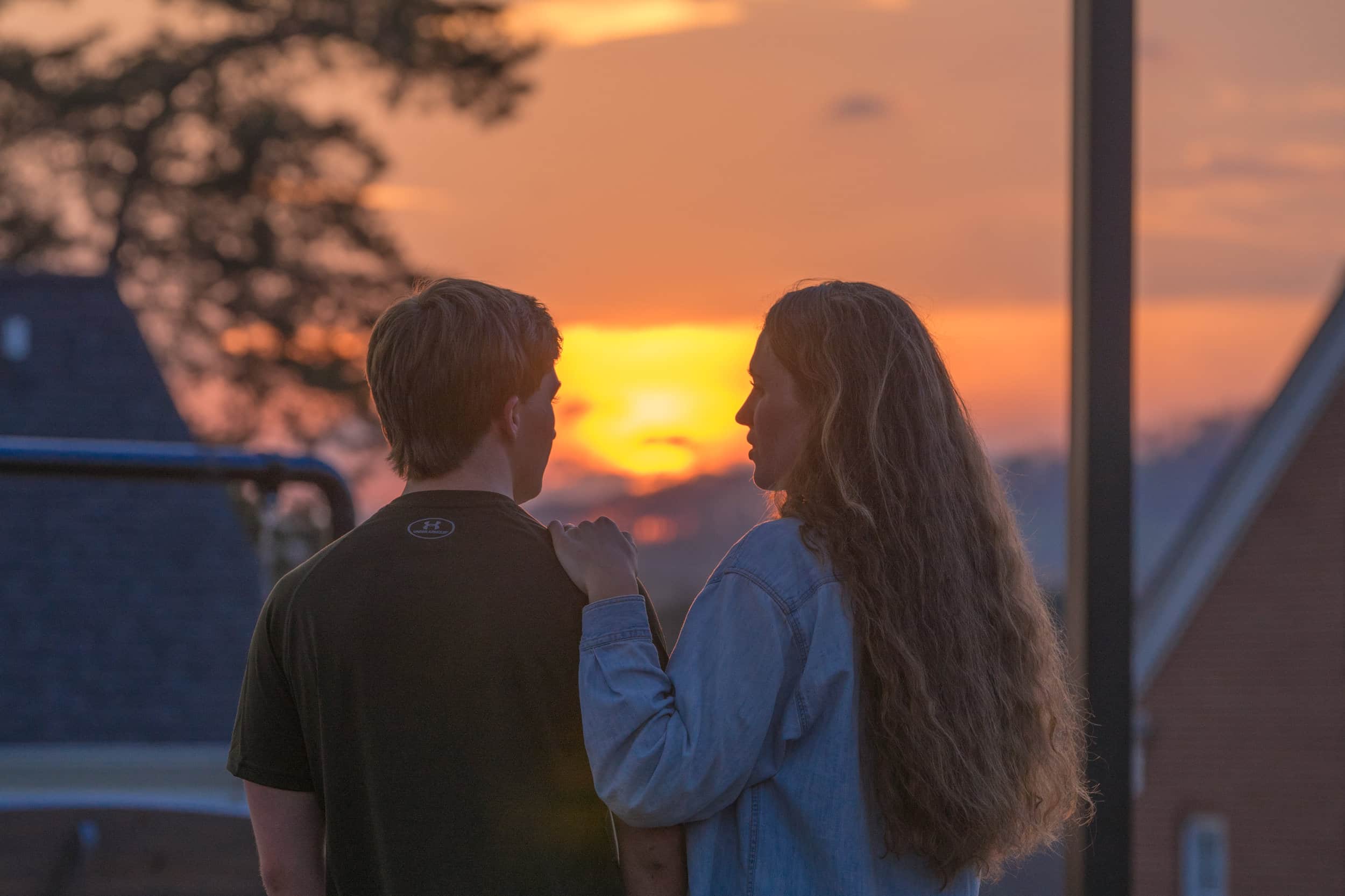 A couple takes in a peaceful moment as the sun sets behind the Blue Ridge mountains.