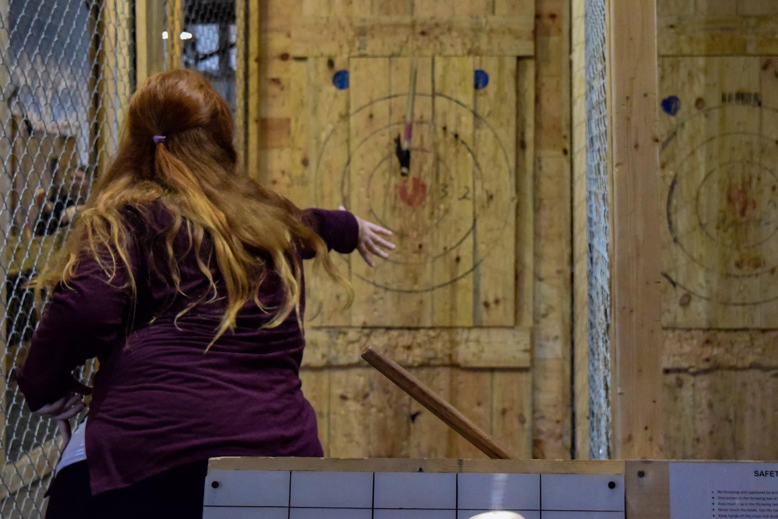 Junior Julie Nalley brings her arms back to throw the axe toward the target.