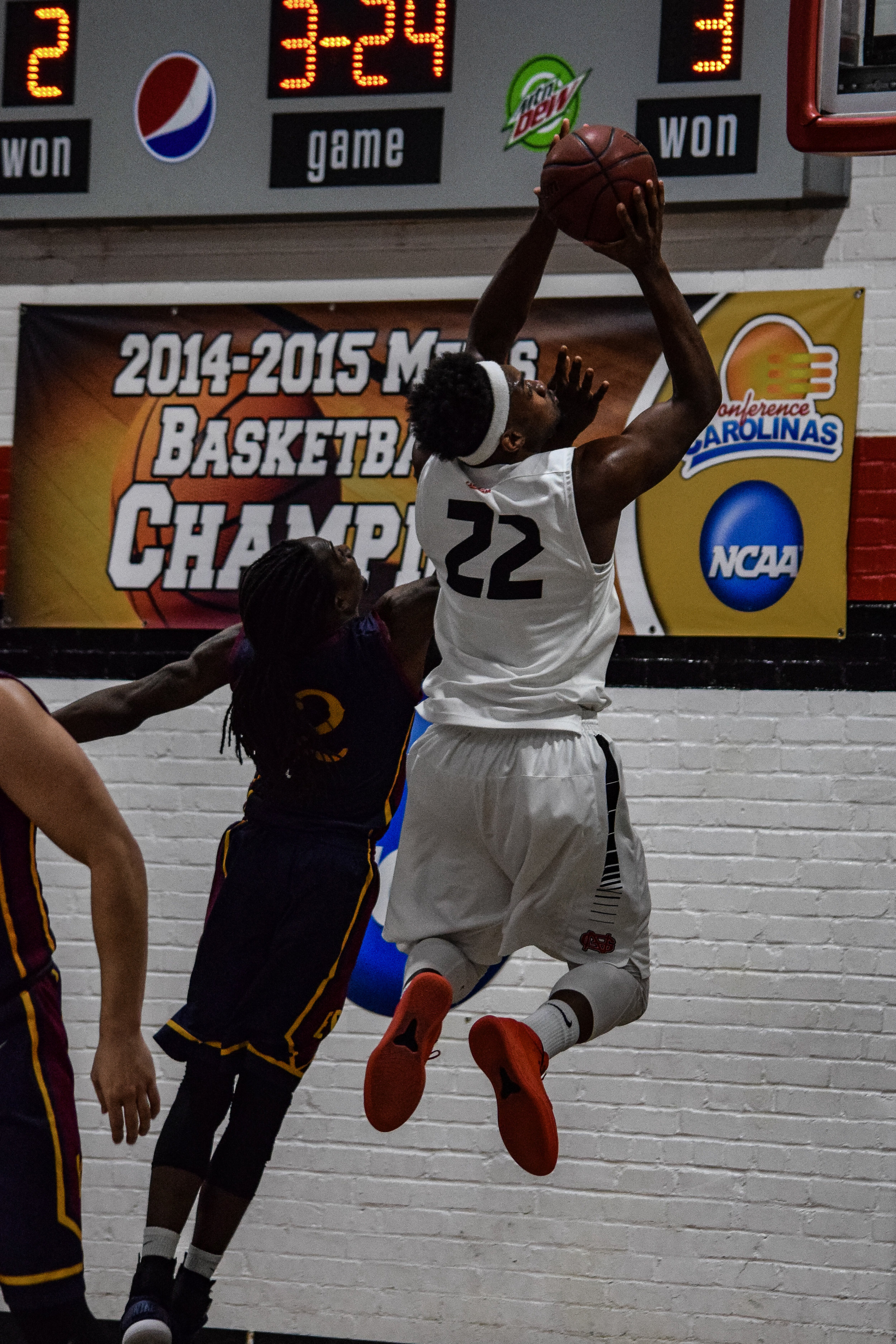 NGU's #22 Roderick Howell tries to score but is being blocked by Emmanuel College's #2 Kurtis Robinson.