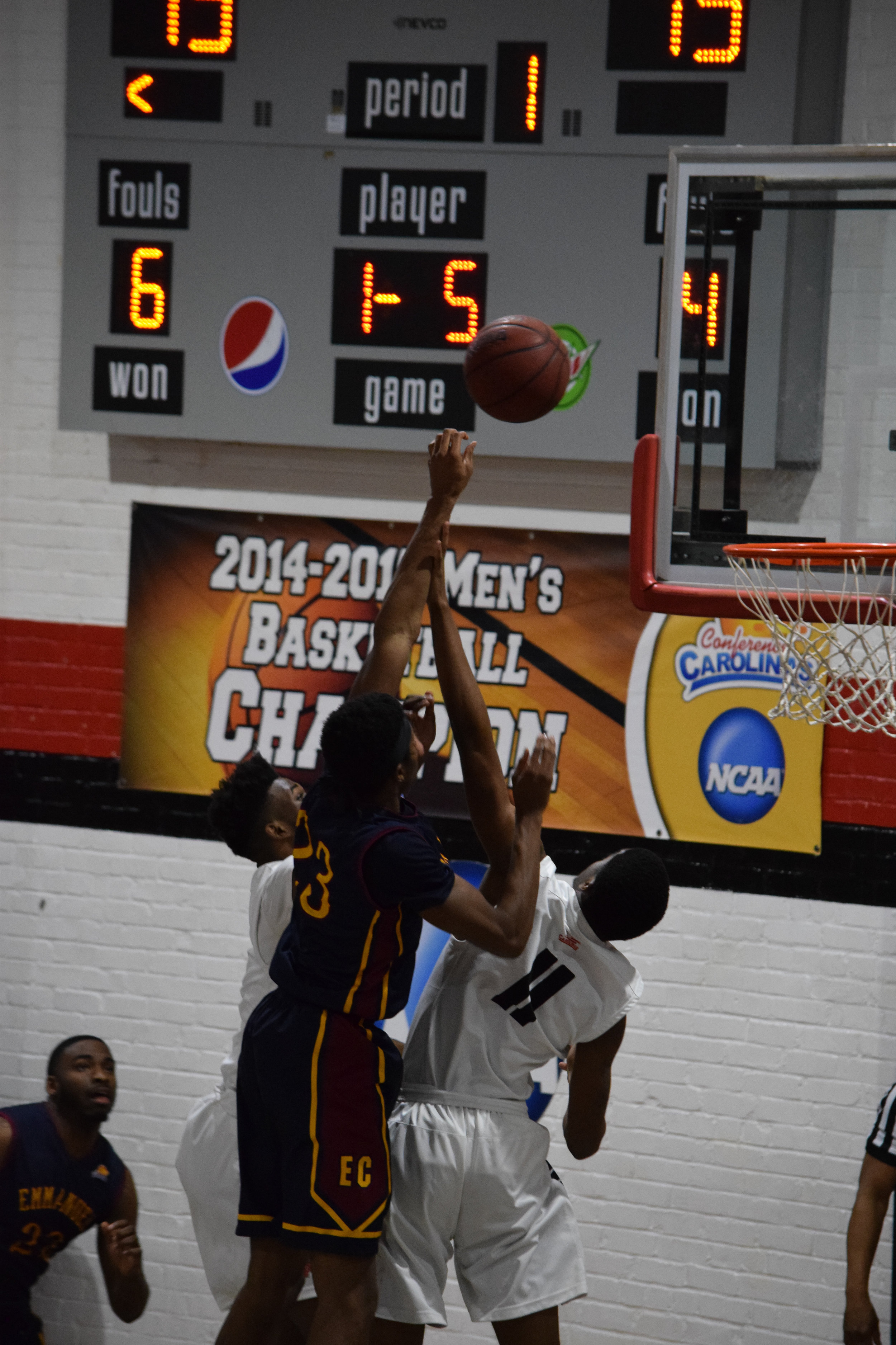 Emmanuel College's #23 Kendrick Colvin goes for a point, but NGU's #11 Jalon Cokley and #2 Moses Merritt try to block.