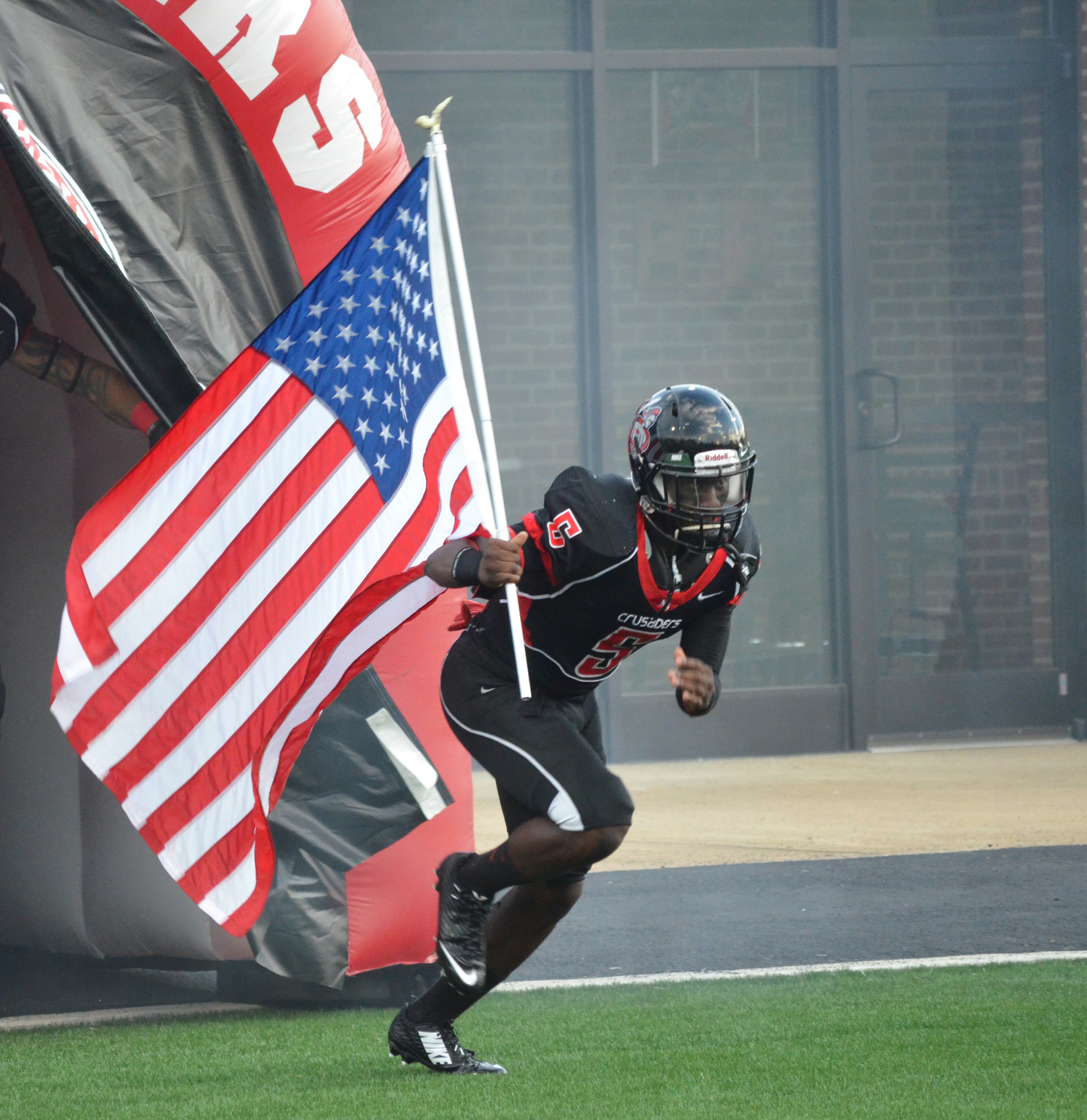  Player #5, Quantel Mack, starts off the game by charging out of the tunnel while carrying the American flag 