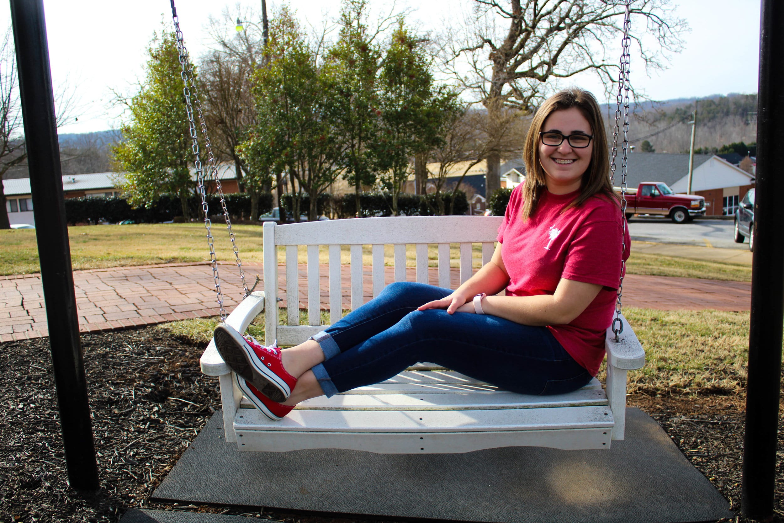 Marissa Holst, a freshman early childhood education major, exhibits her encouragement for the awareness of heart disease by wearing red as she swings outside of Neves.