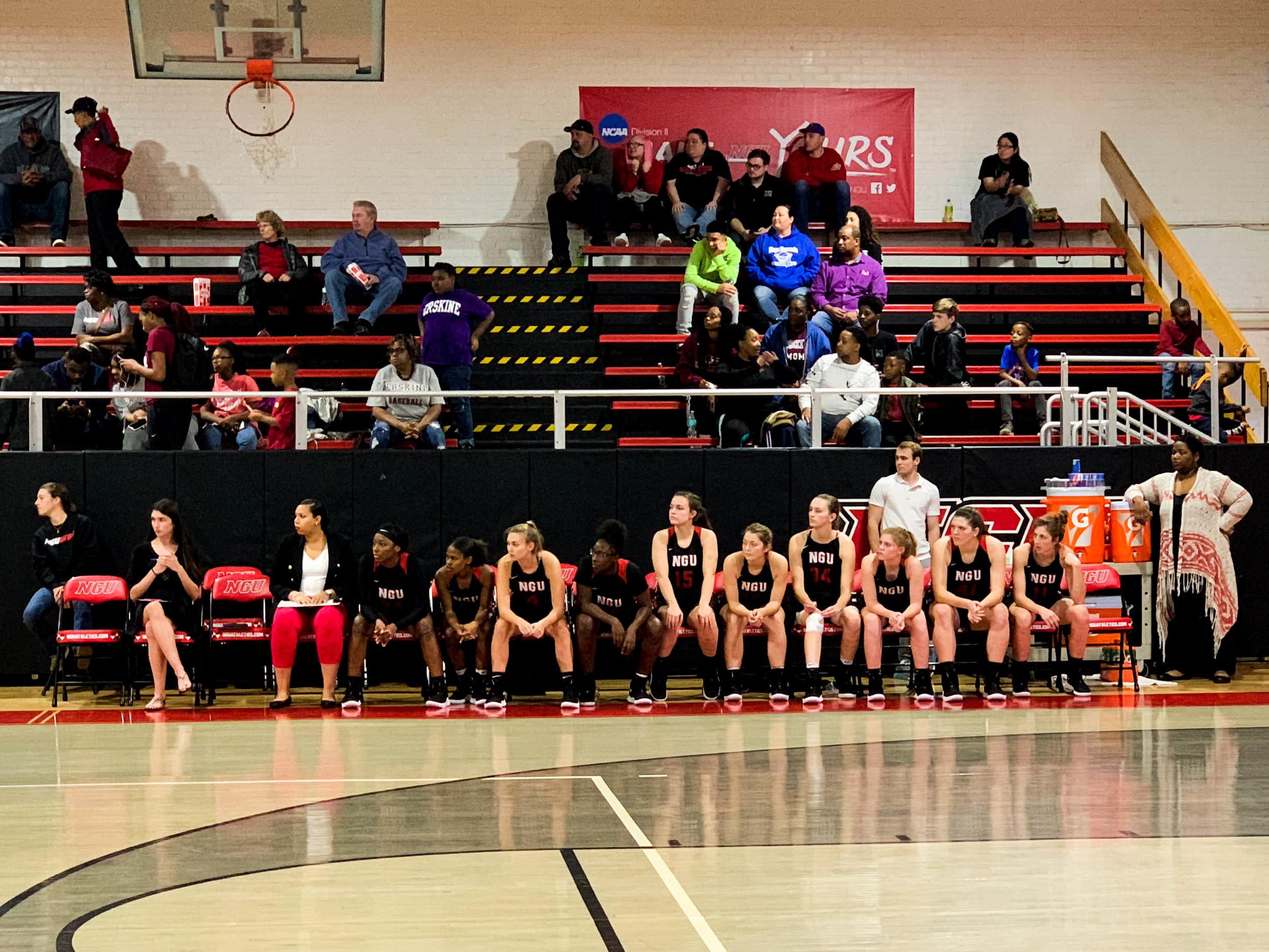 The NGU team watches as its teammates play.