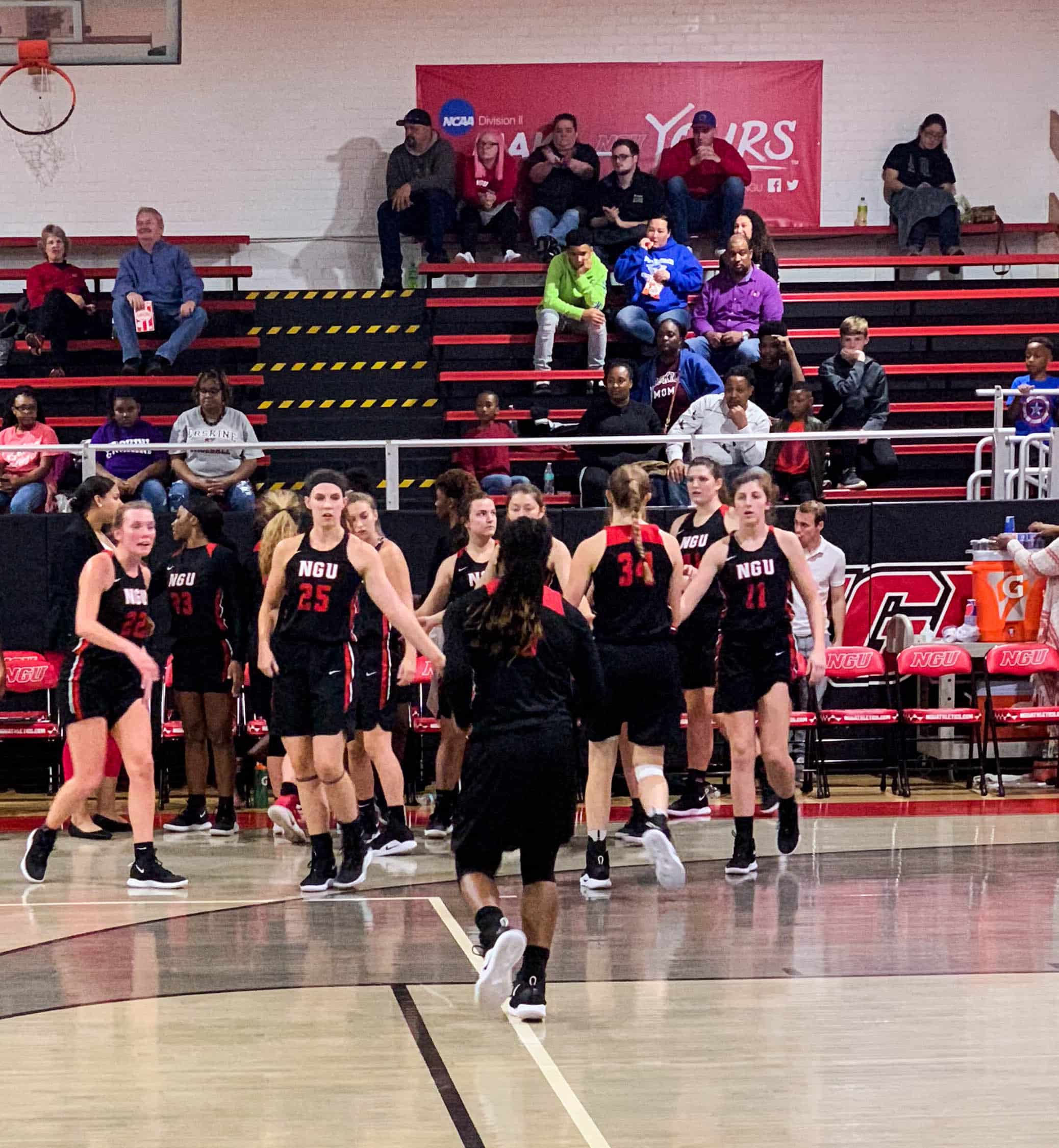 The players on the bench high five sophomore, Kira Bell, as she runs off the court during a time out.