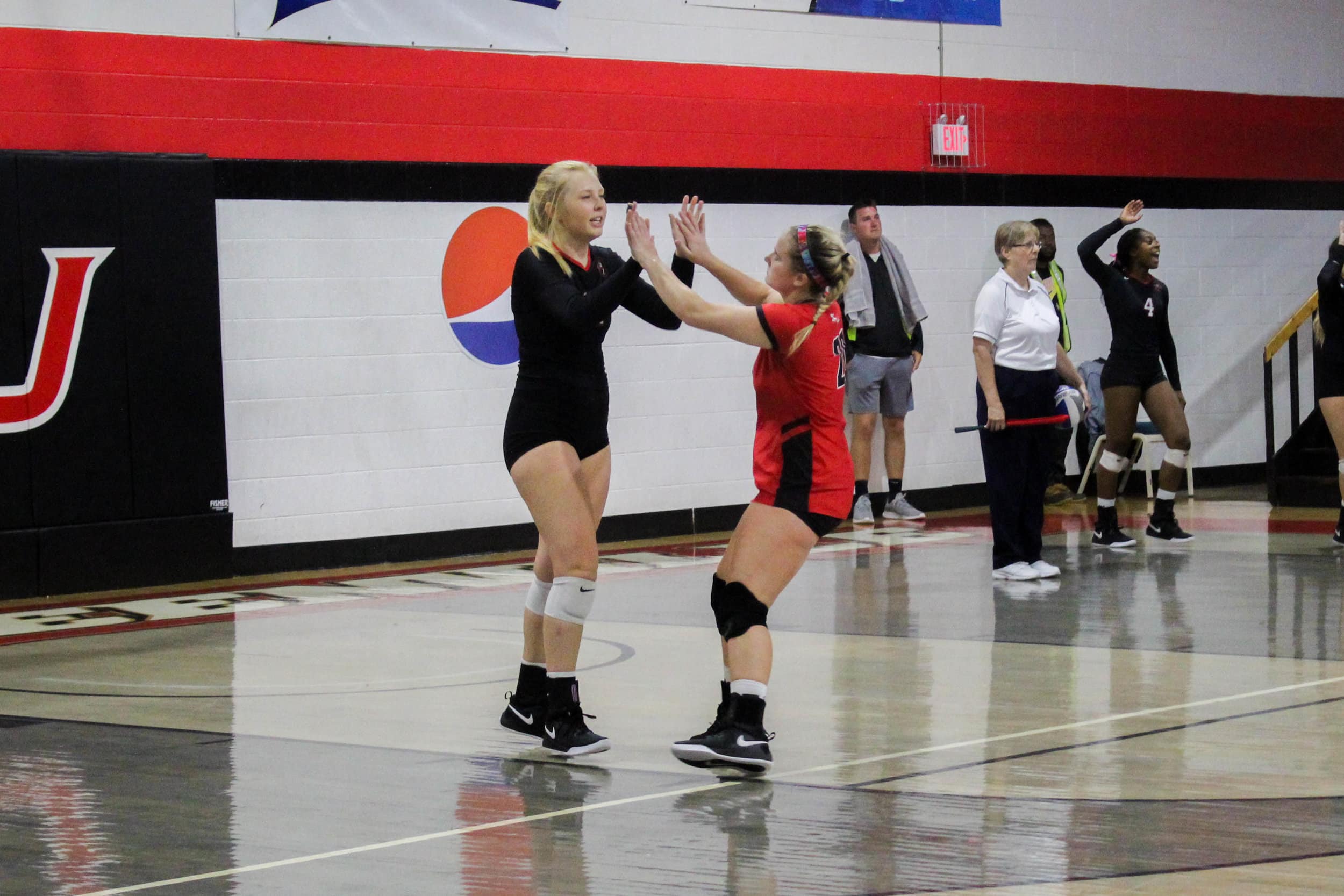 Freshman Whitley Kahler (20) congratulates senior Sara Miller (11) after Miller served a ball that resulted in a point for NGU.