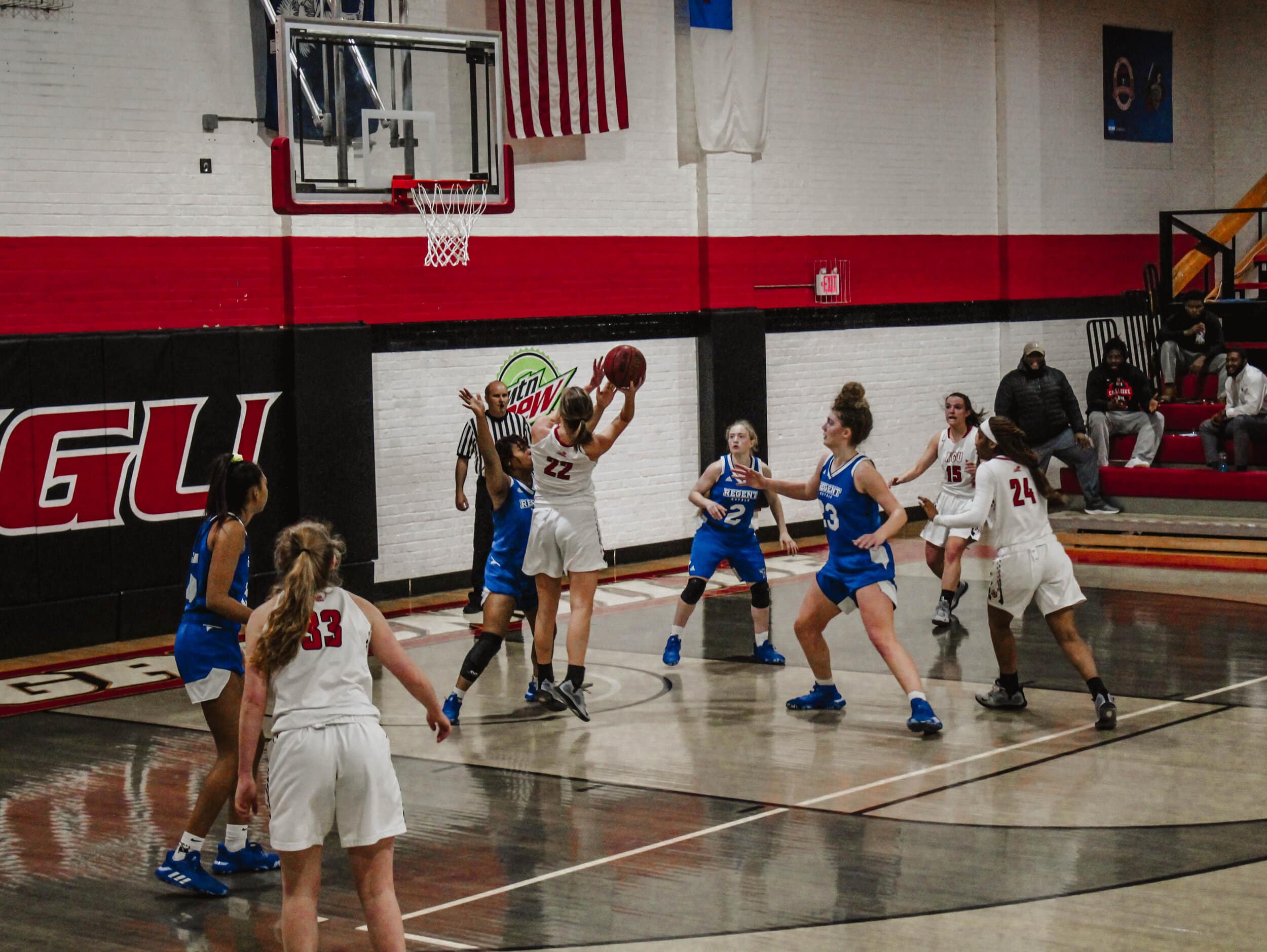 Bree Stoddard (22), a junior guard takes a jump shot while her teammates run toward the basket to rebound.