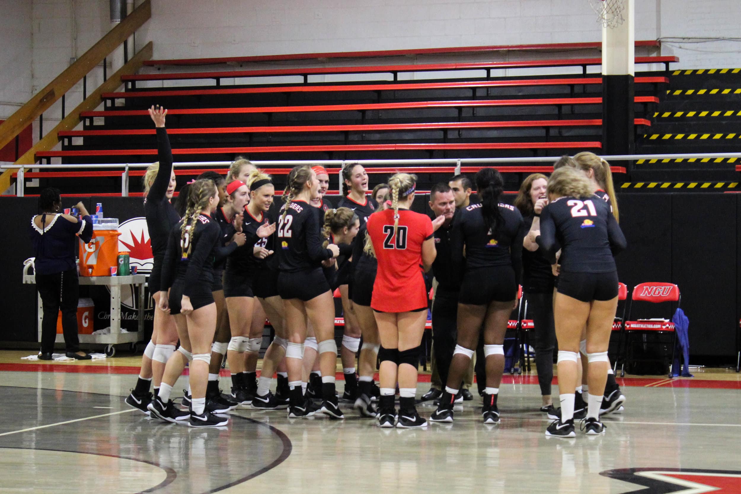 After winning a set, the NGU womens volleyball team huddle together to cheer on the players that were on the court.