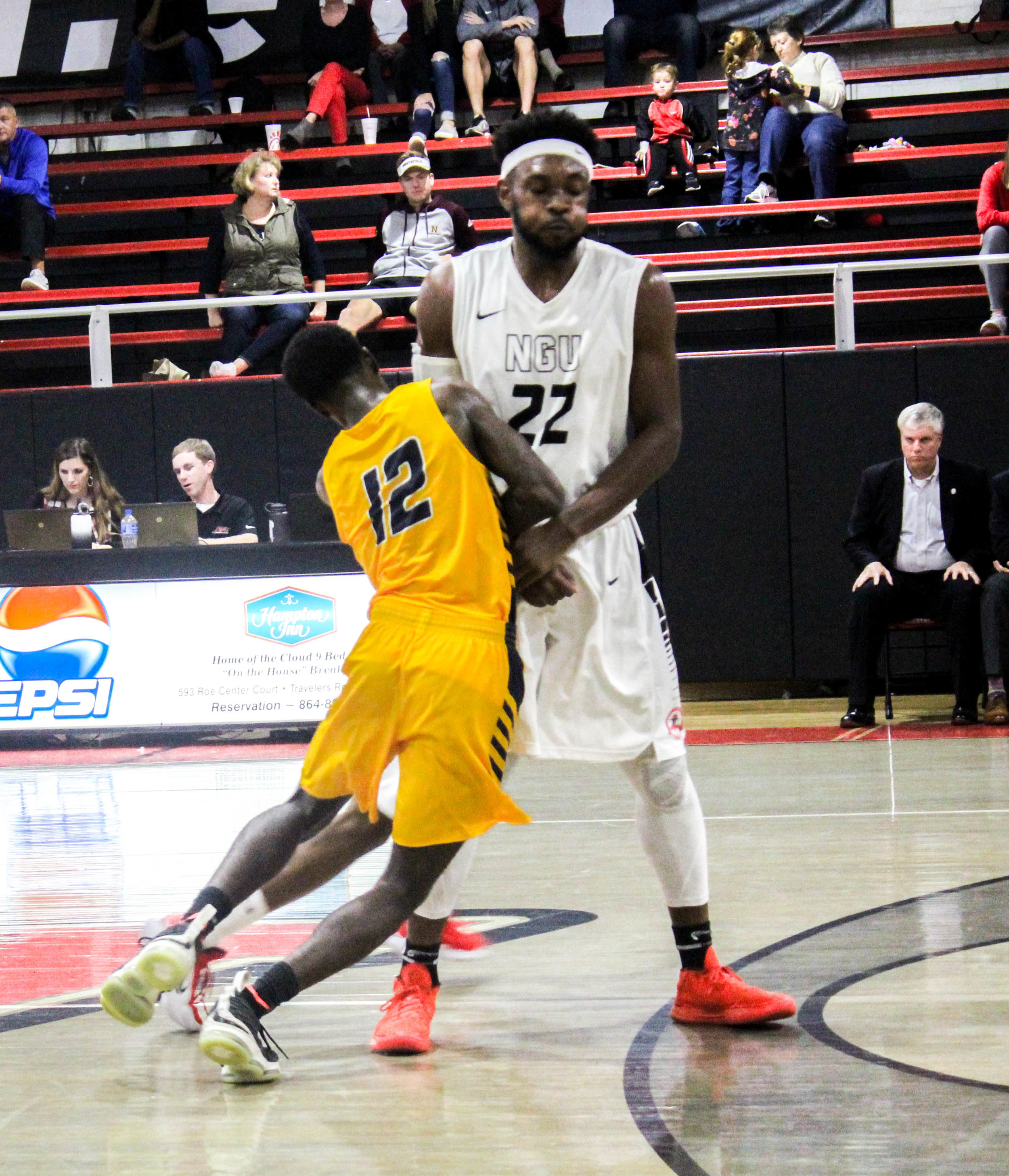 A player from CIU falls into Howell (22) as he sets a pick for his teammate.