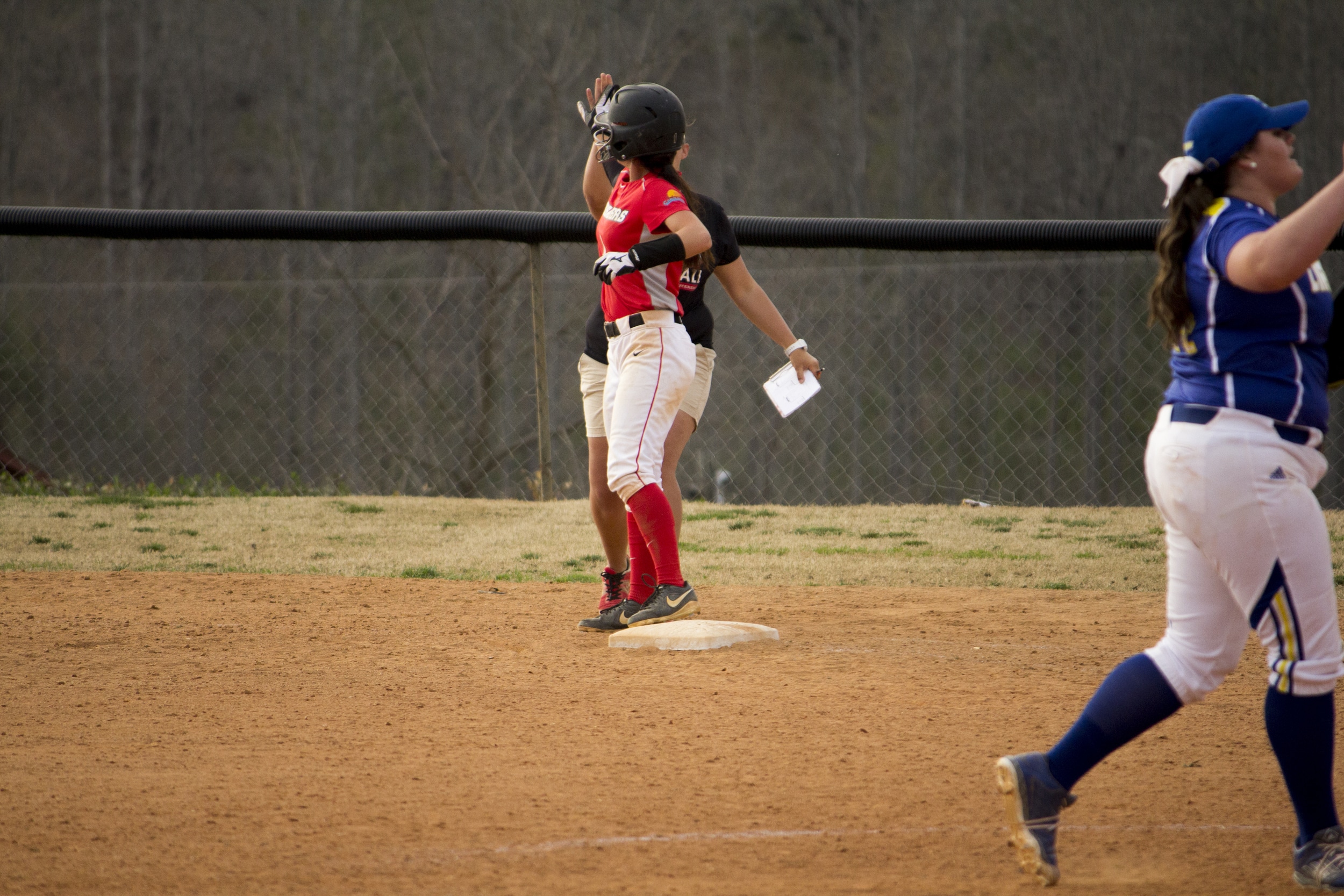  Sophomore Shayna Finley gets a high five from her coach after her sprint to first base.&nbsp; 