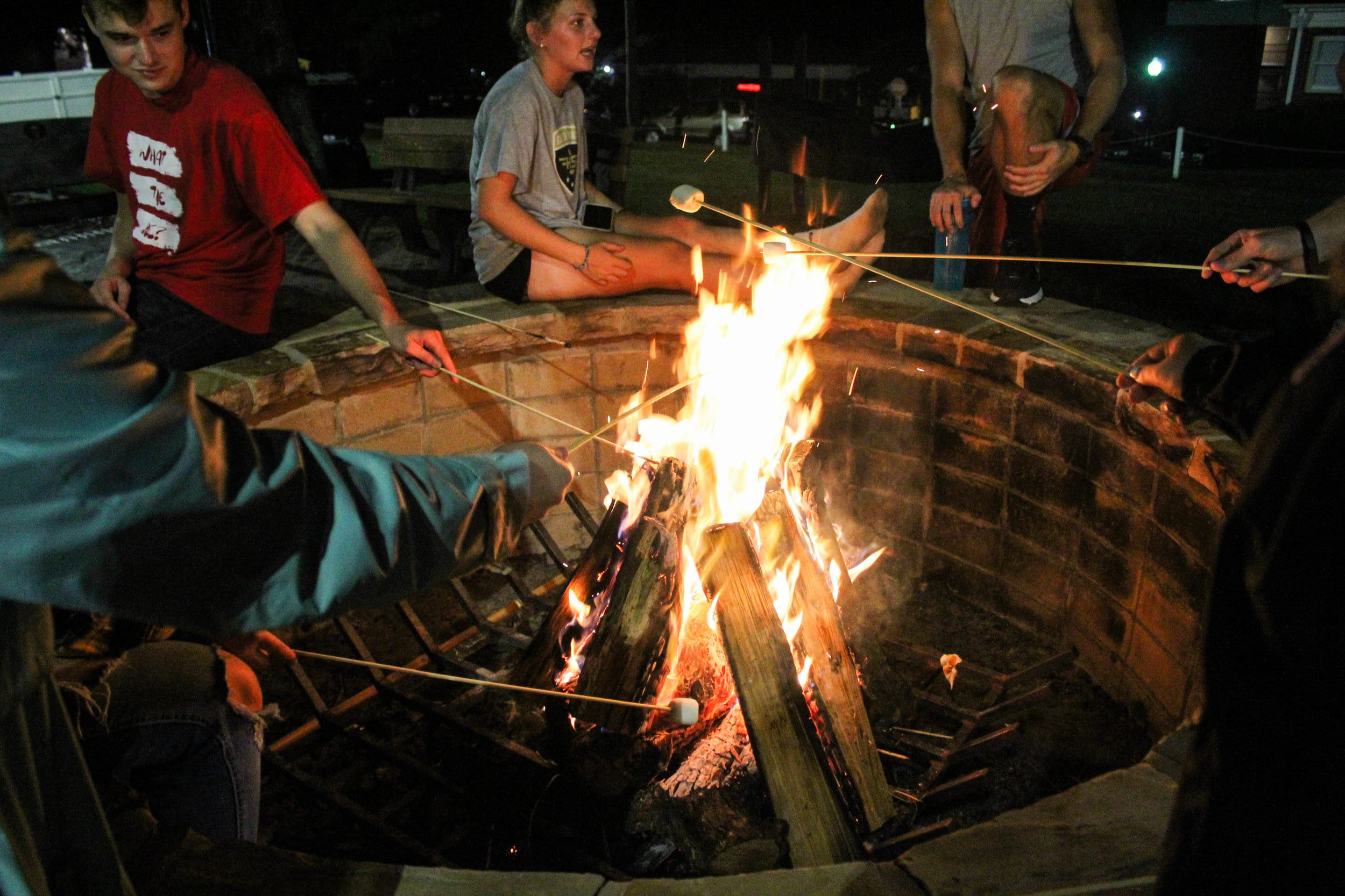 Students gather around the fire pit and roast marshmallows to make s’mores while the watch the volleyball tournament.
