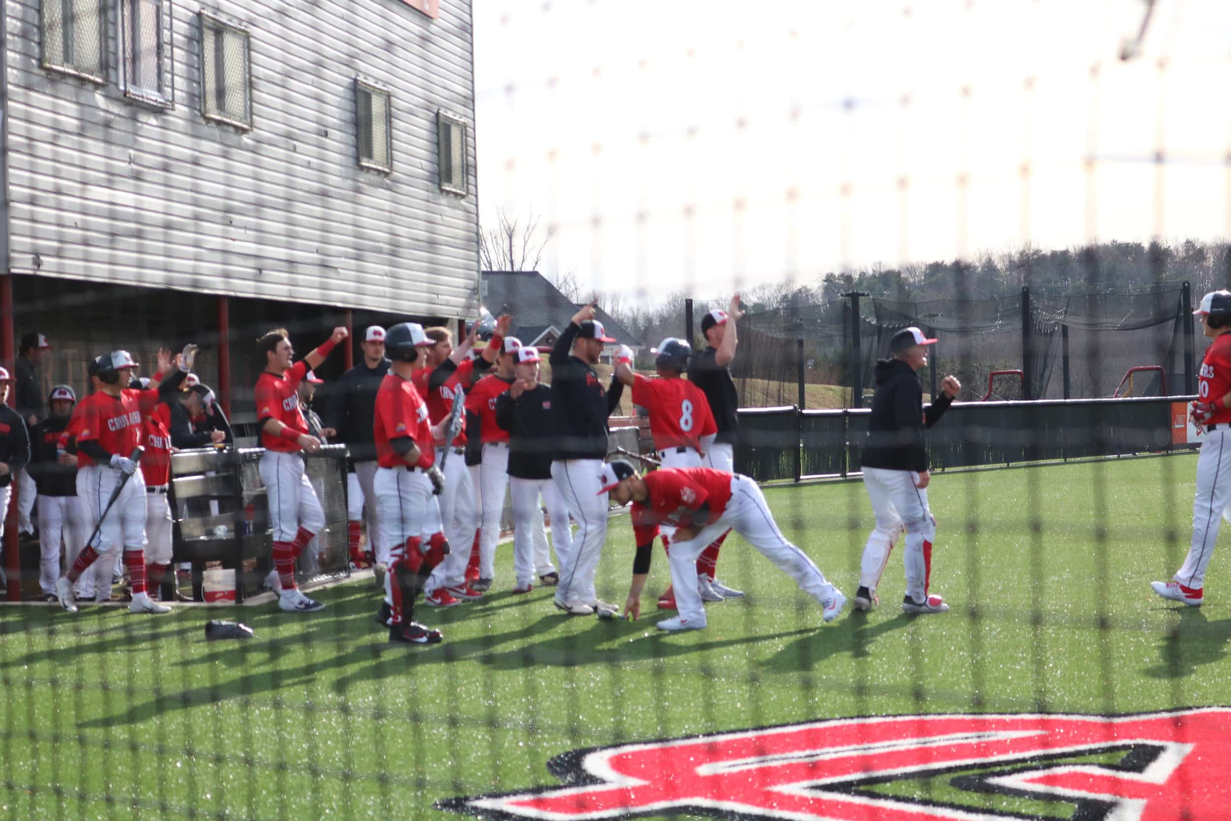 The Crusaders high five Whitehead (8) as he heads in from home plate, scoring the first point of the season.