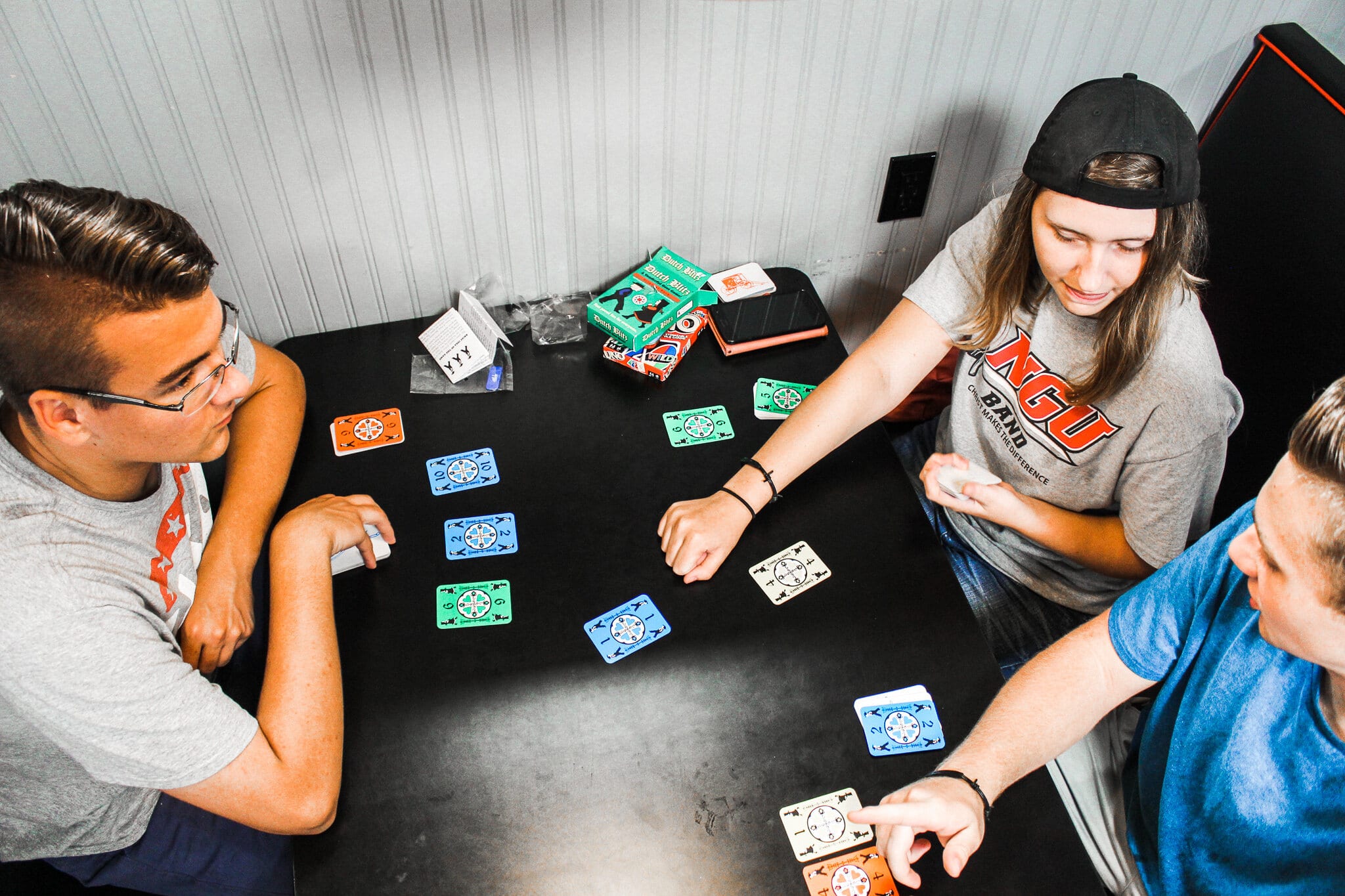 Brandon Folz, Biology major, Madeline Worsham, Elementary Education major, and Brian Smith, Health Science major, play cards in the Student Center.