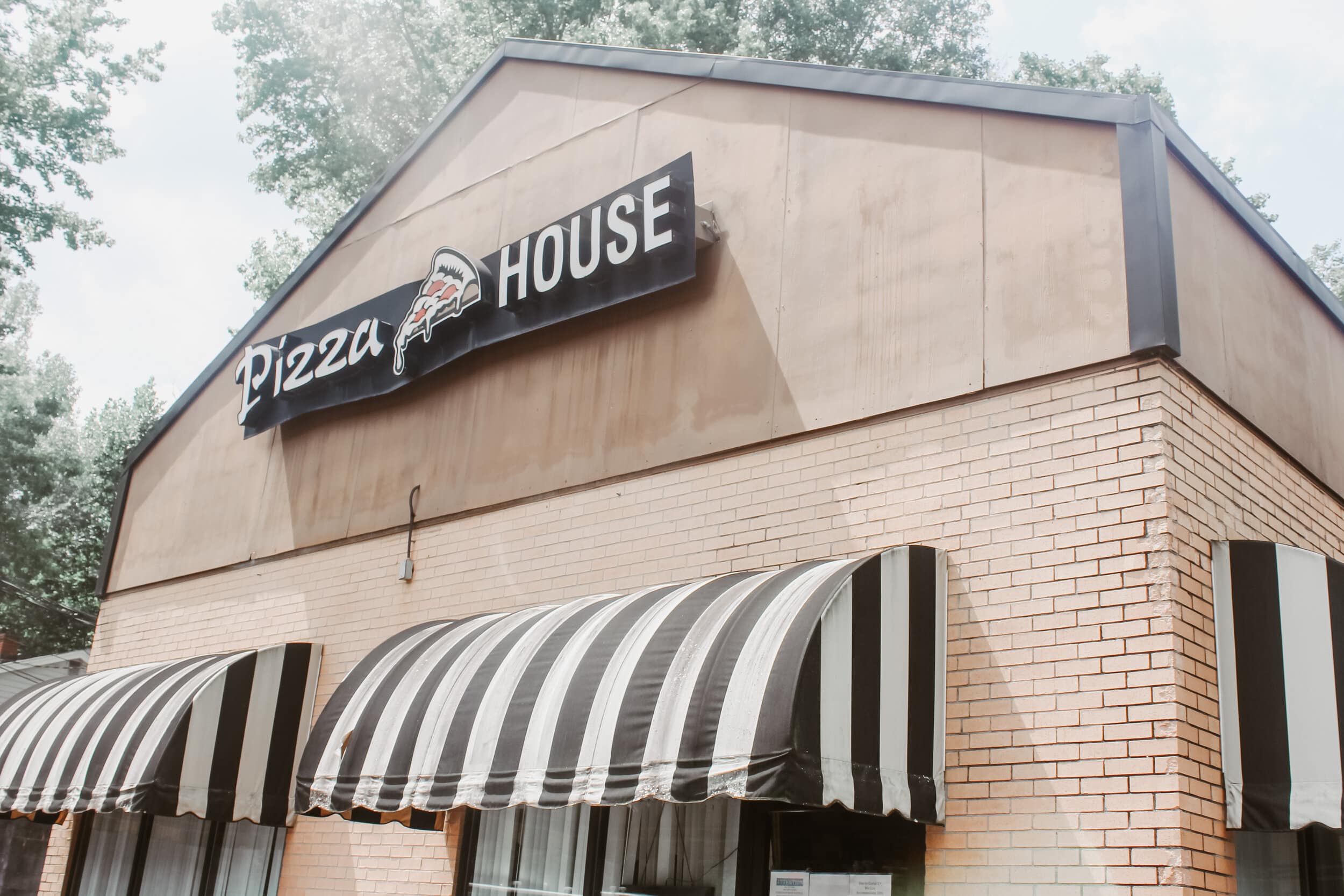 The front of the Pizza House building is depicted on a cloudy day.