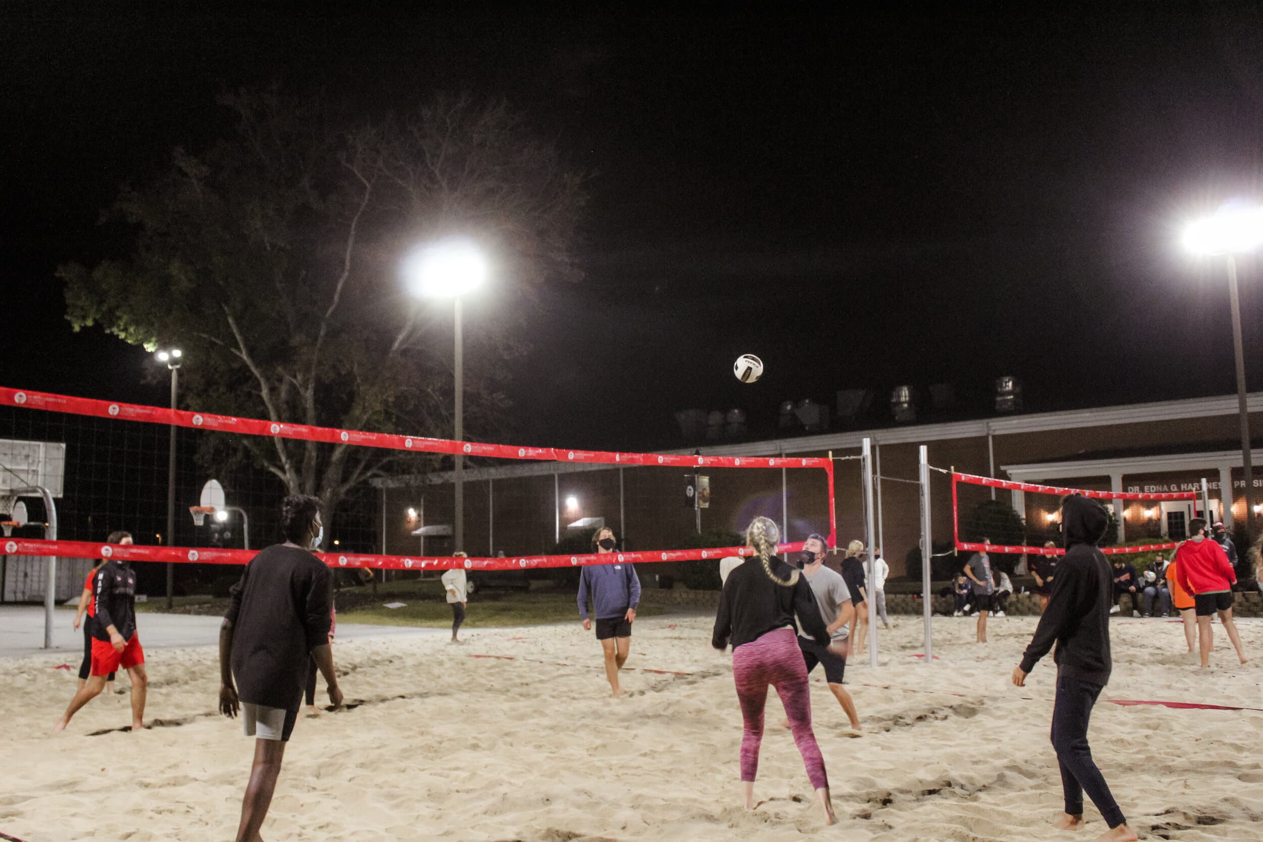 This intramural volleyball team is one of the four teams fighting for the championship title. Friends and peers of players, all masked up, join with them at the sand volleyball courts.