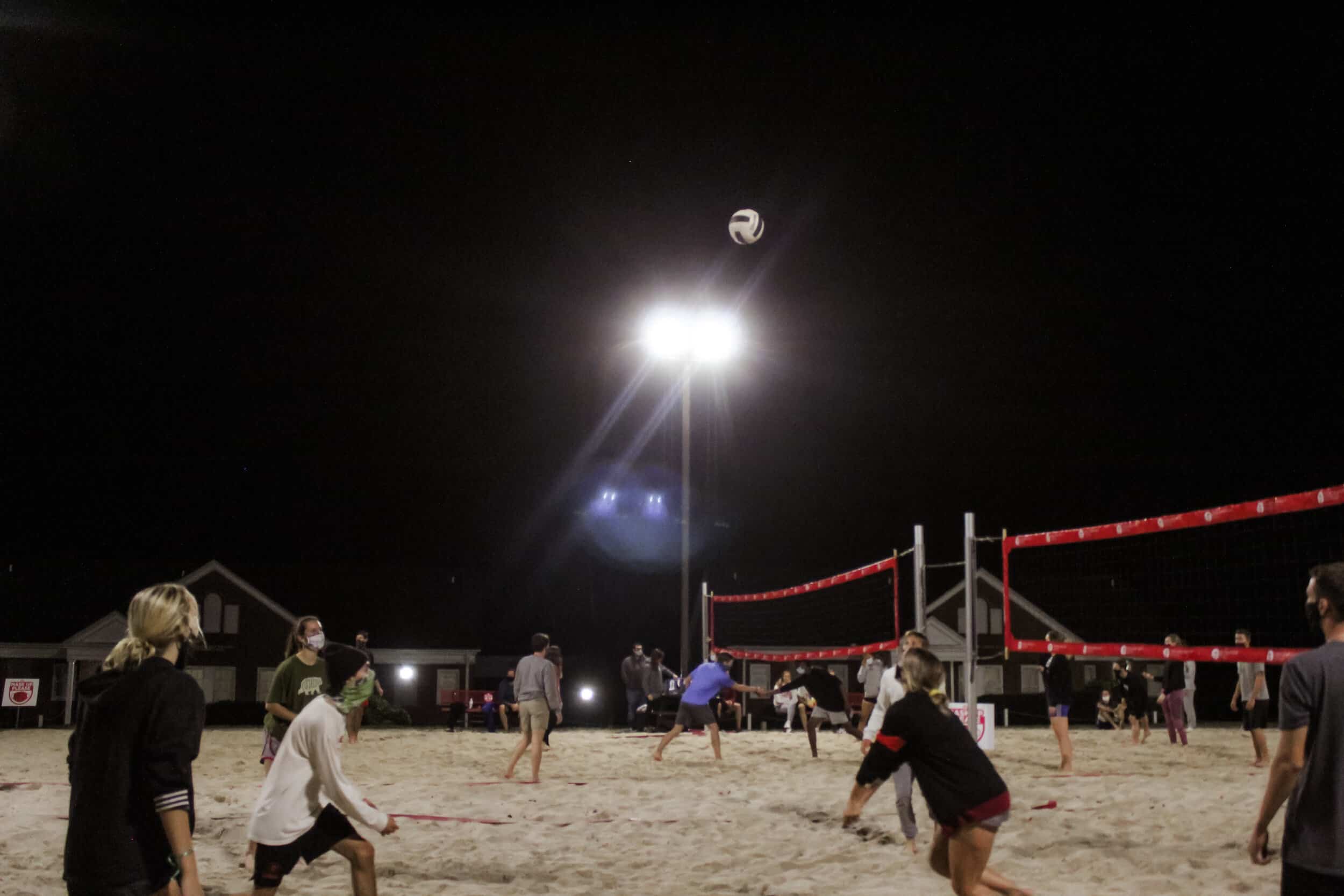 Intramural volleyball team members participate together to return the volleyball to the other side of the net.