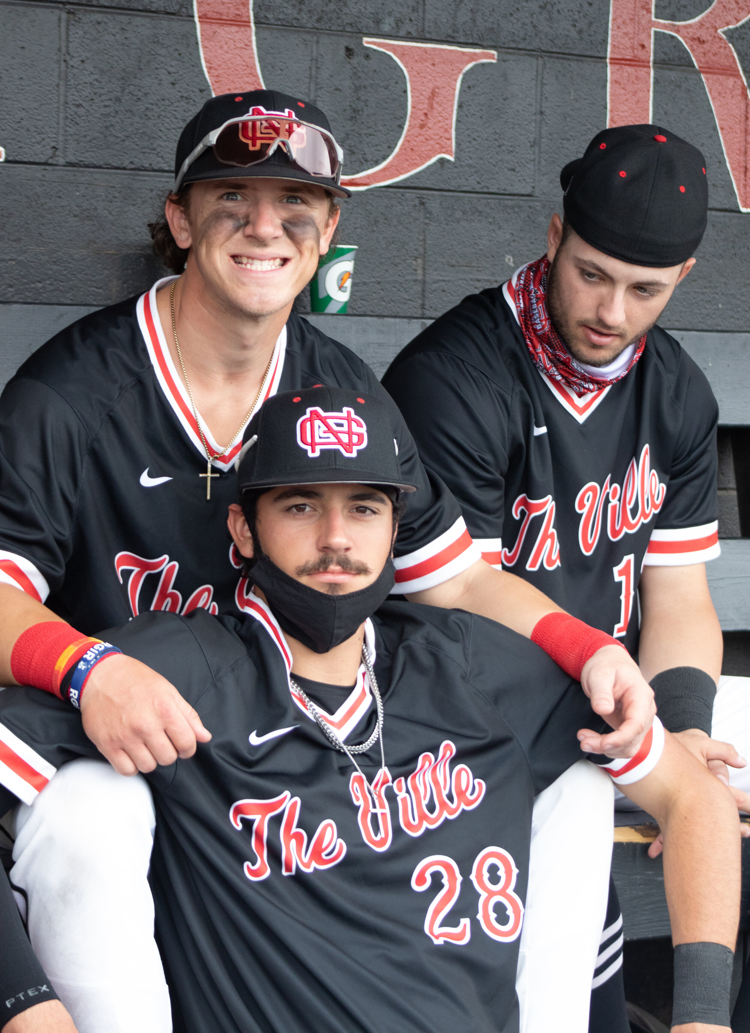 Second baseman Doug Angeli, outfielder AJ Kaminsky and first baseman Dawson Price pose in the dugout as they cheer their teammates on.