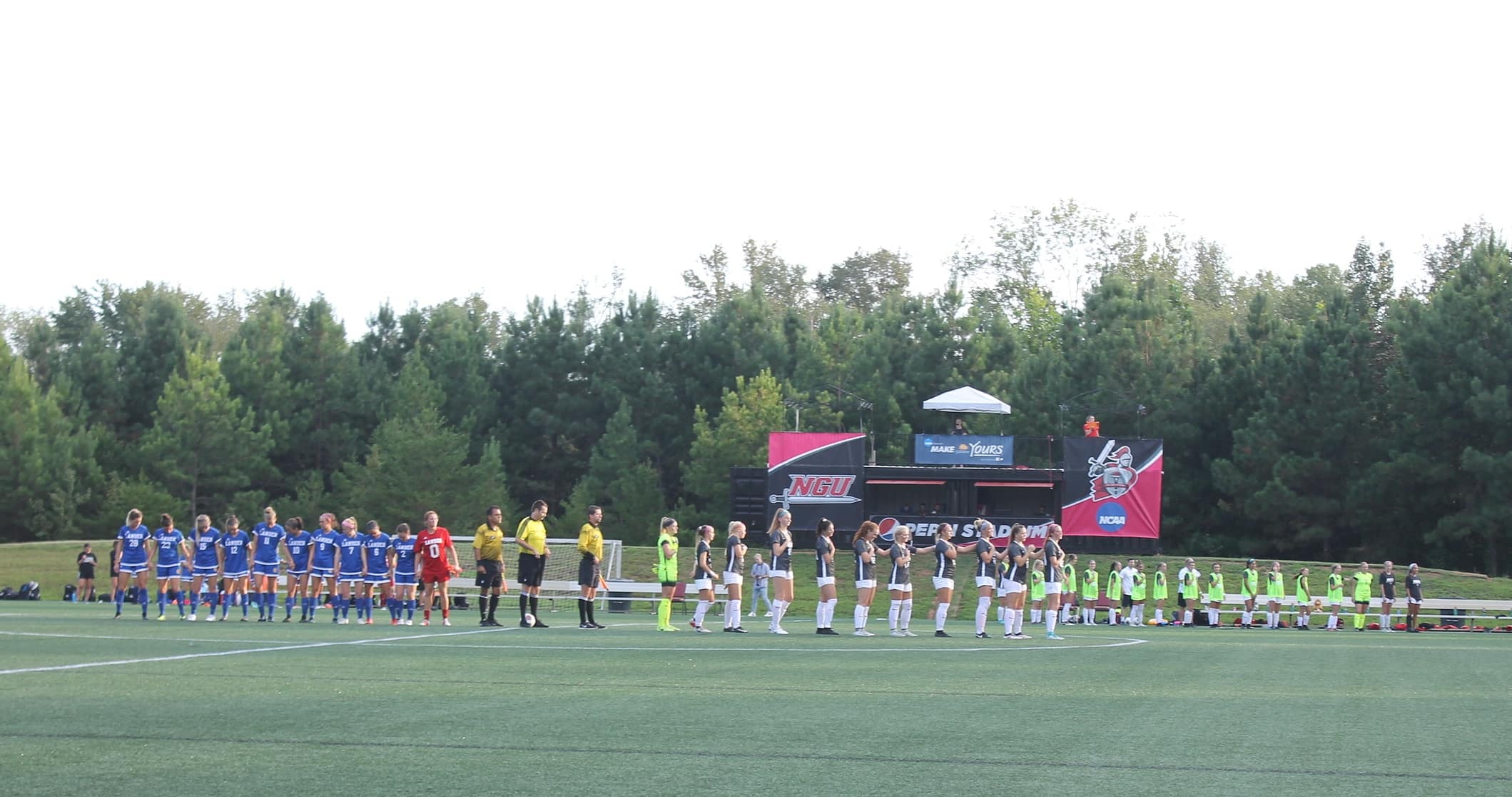 Both teams standing together for the pledge of allegiance.