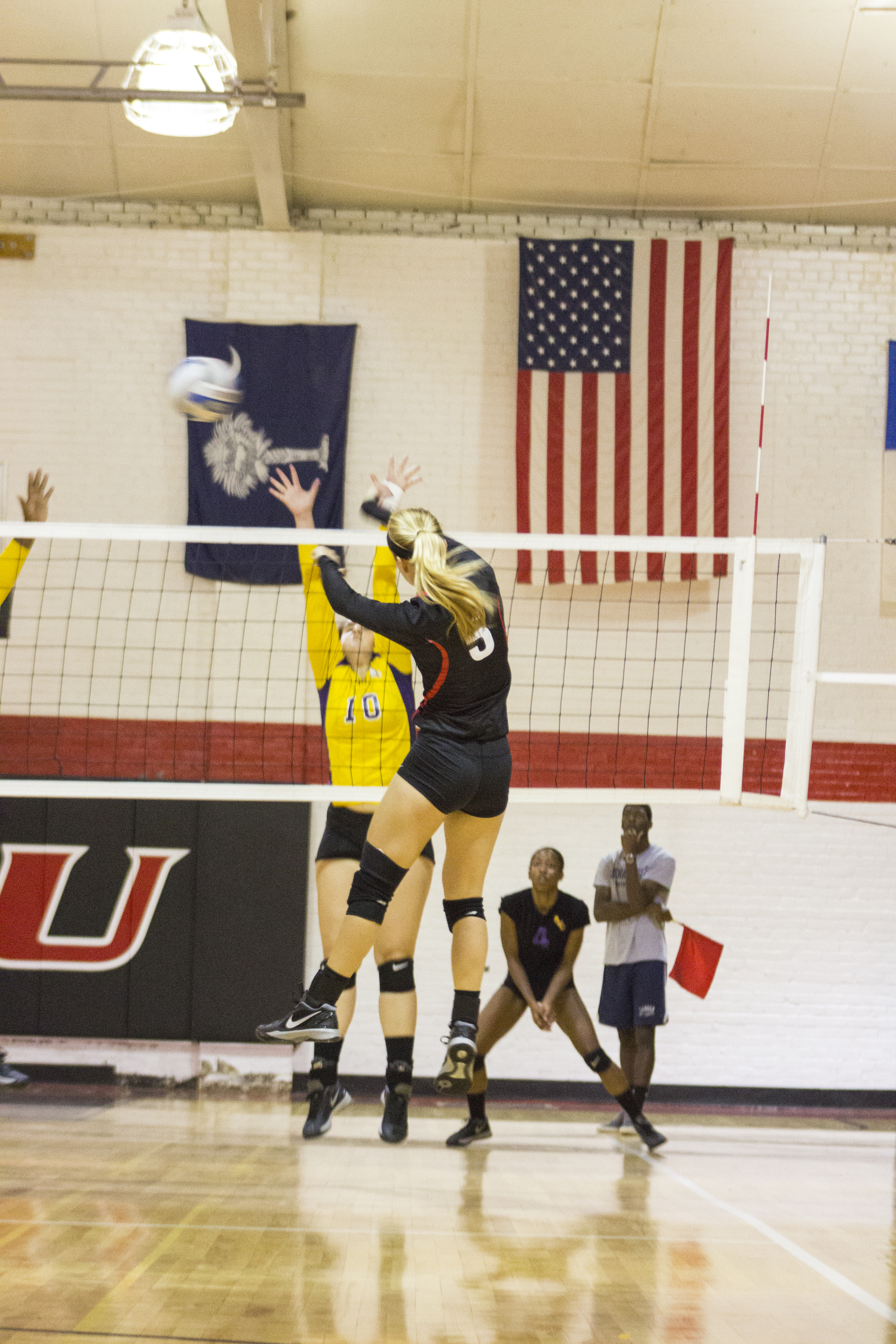  Junior Taylor Dupes jumps to spike the ball across the net between two opponents. 