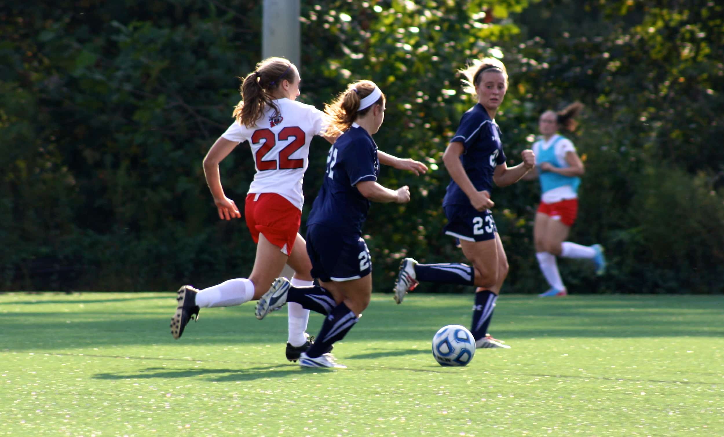  #22, Kathryn Allen, runs between two opponents in order to reach the ball. 