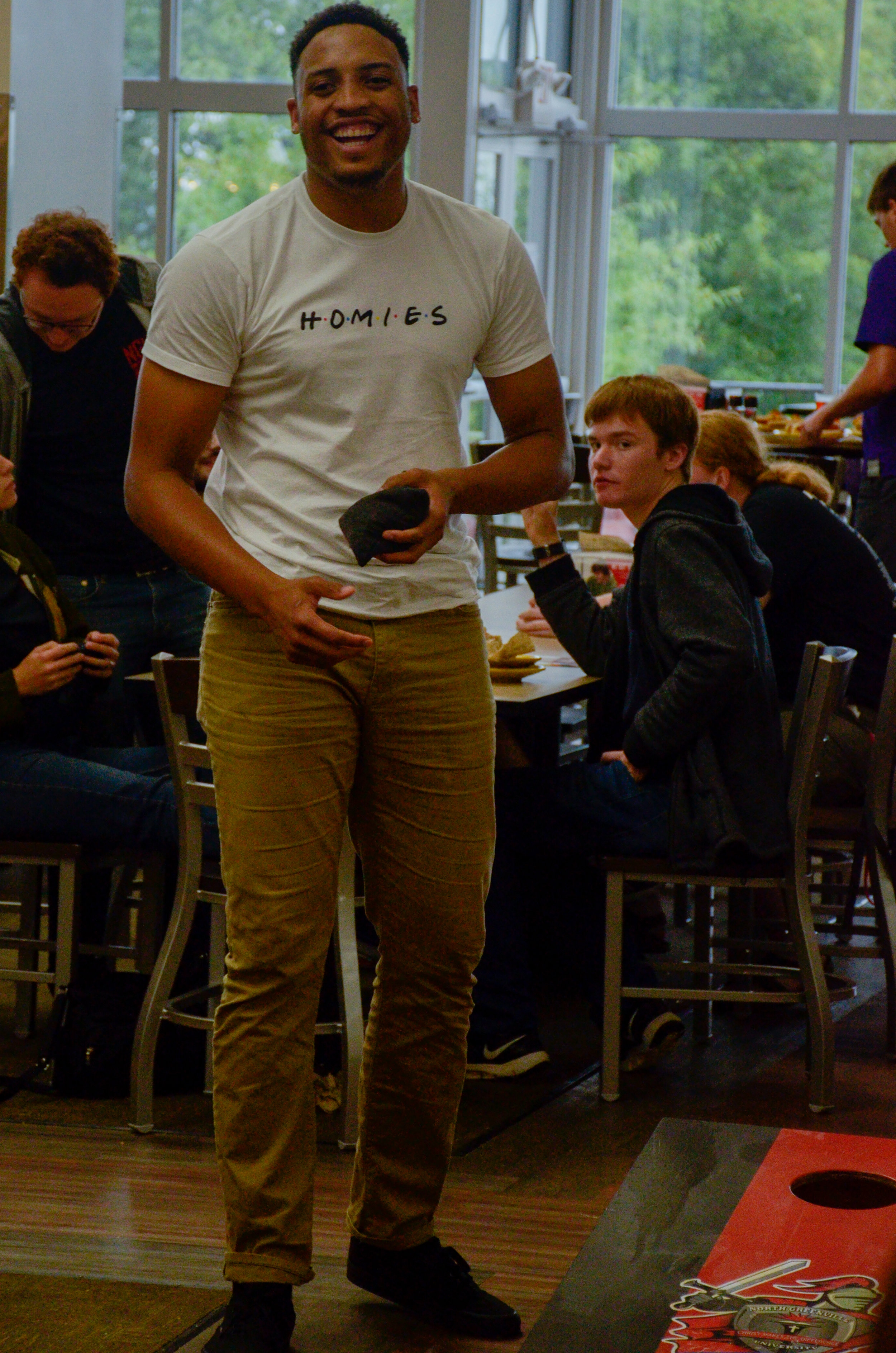 Chris Taylor, junior, gets his mind off of classes while playing Corn Hole in the cafeteria during a tailgating party before the football game on Thursday.
