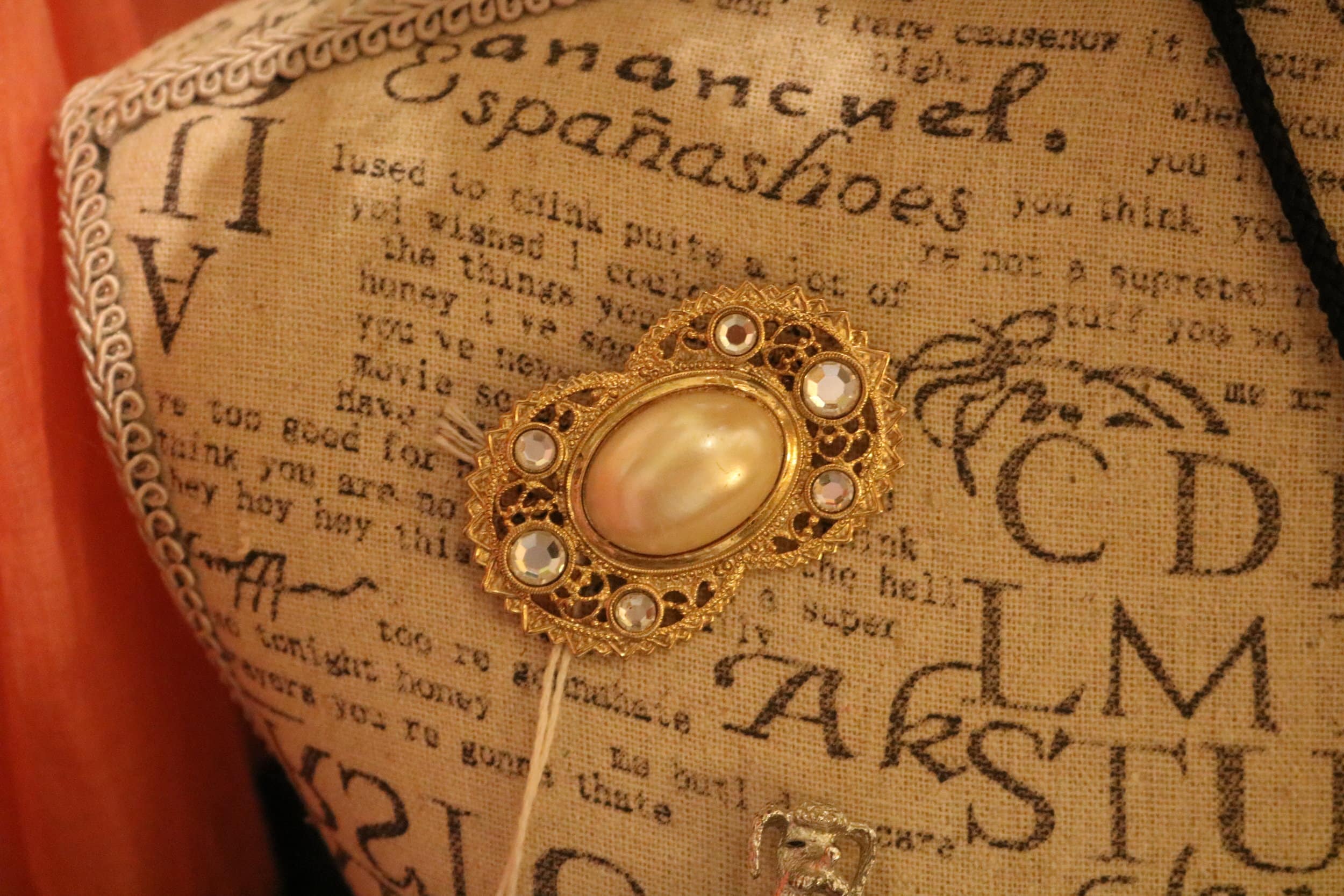 A gold and pearl broach pinned on a mannequin.