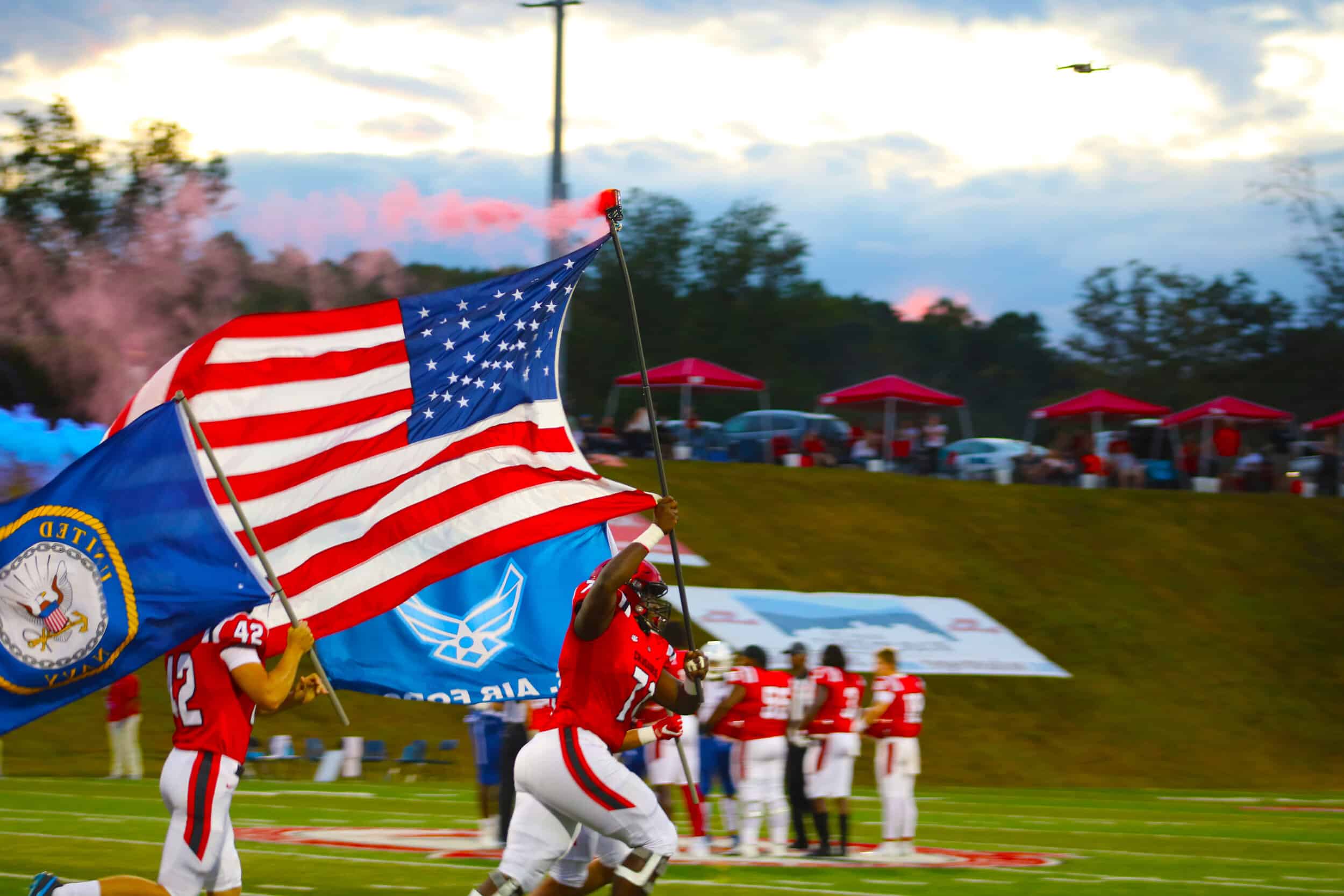 Sophomore Tyler Lilly (77) leads the Crusaders out of the tunnel before the game, holding our countrys flag before the beginning of the game.