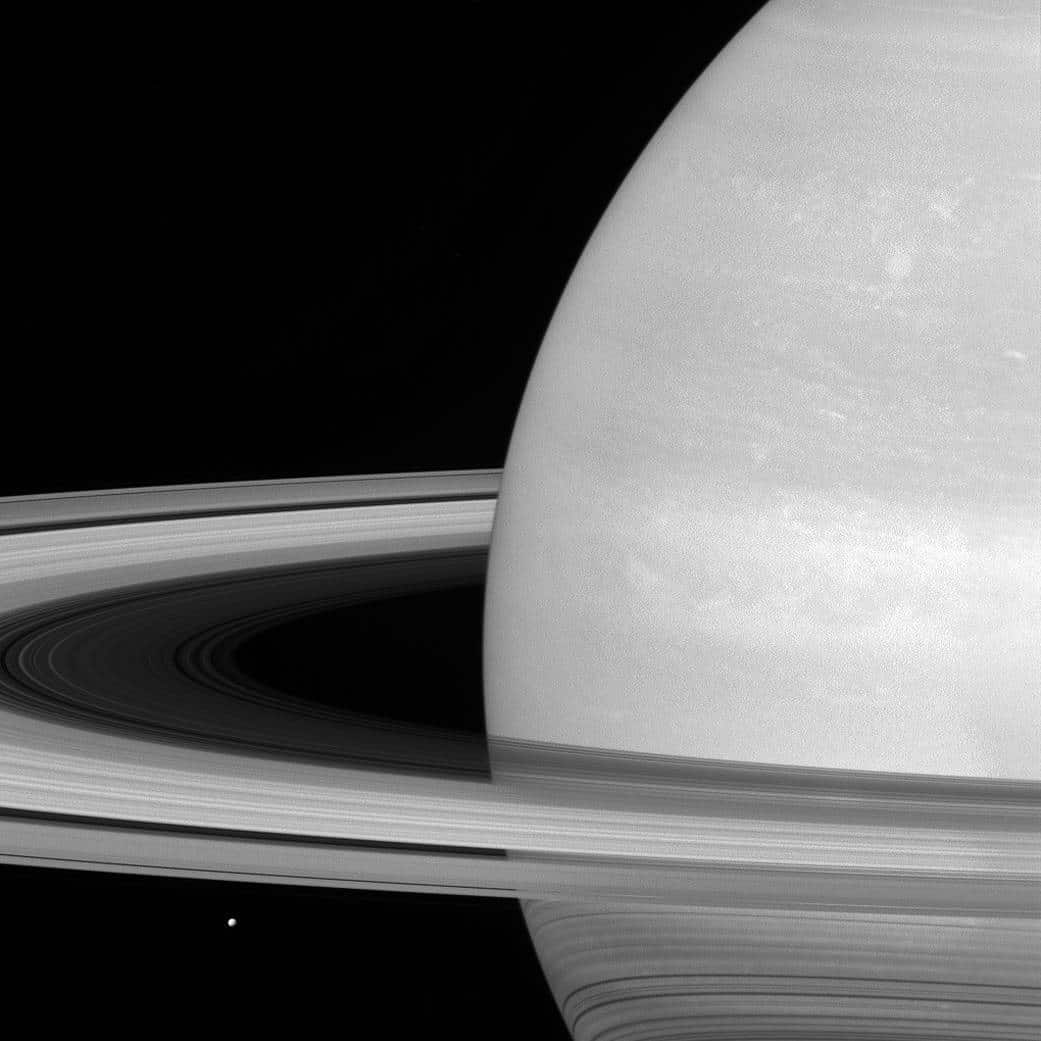 6. Tiny MimasMima, characterized by its covering in ice, rests beneath Saturns rings.