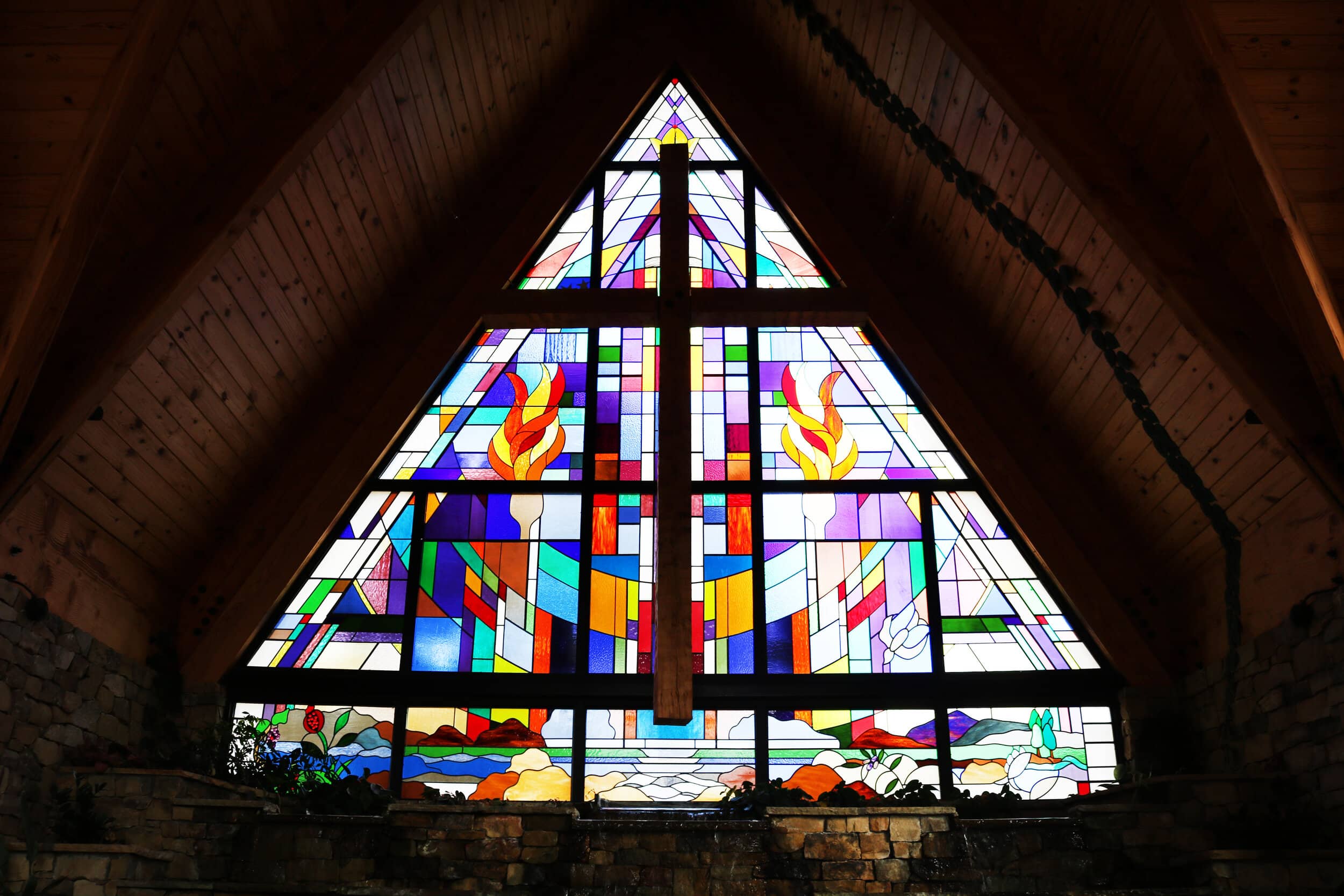 The stained glass window that depicts different verses from the Bible. To the left of the stained glass window, there is a plaque depicting the different meanings and verses of some of the symbols in the stained glass.